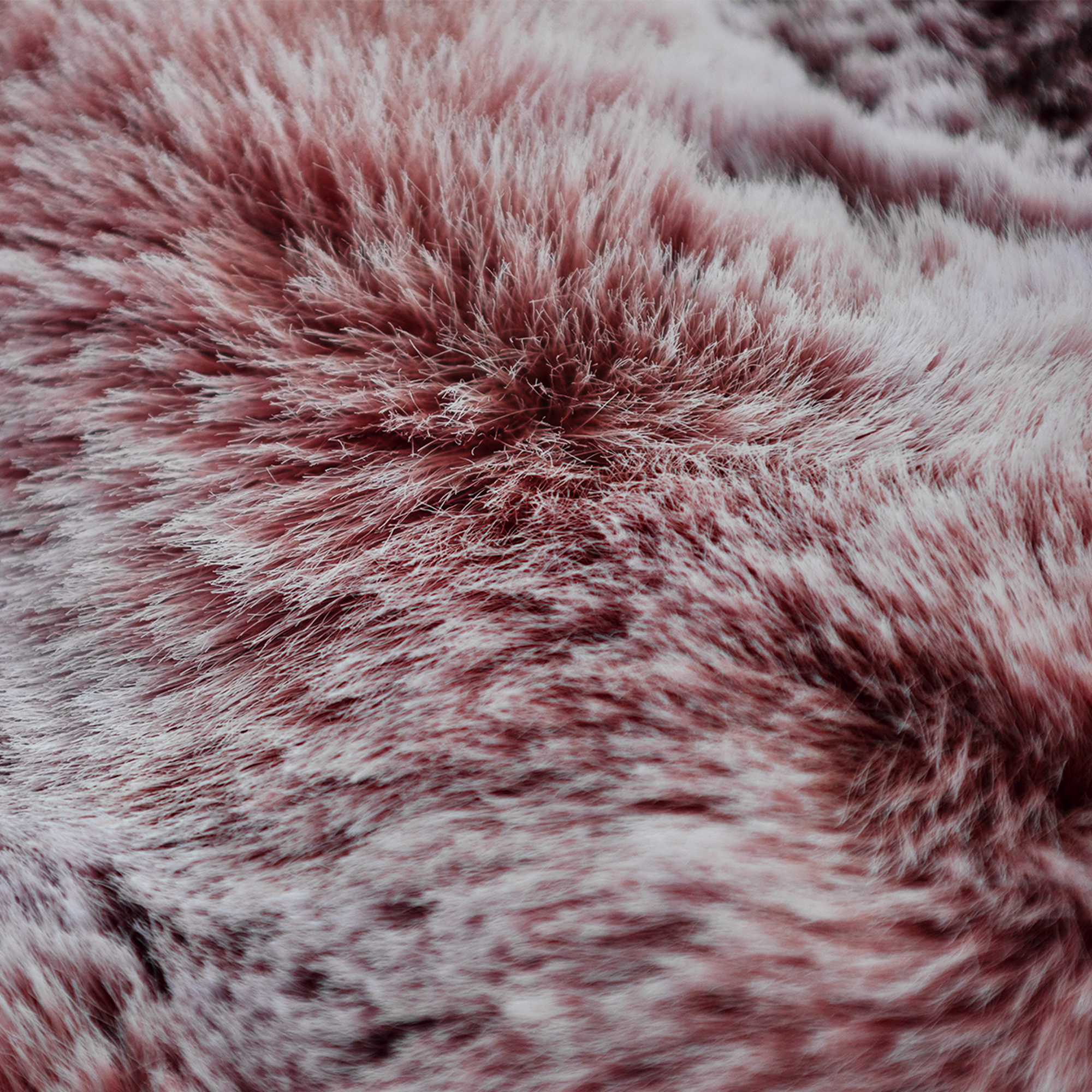 Close-up van een zachte, imitatiebont textuur. De kleuren zijn tinten roze en wit, wat een zachte, uitnodigende uitstraling creëert.