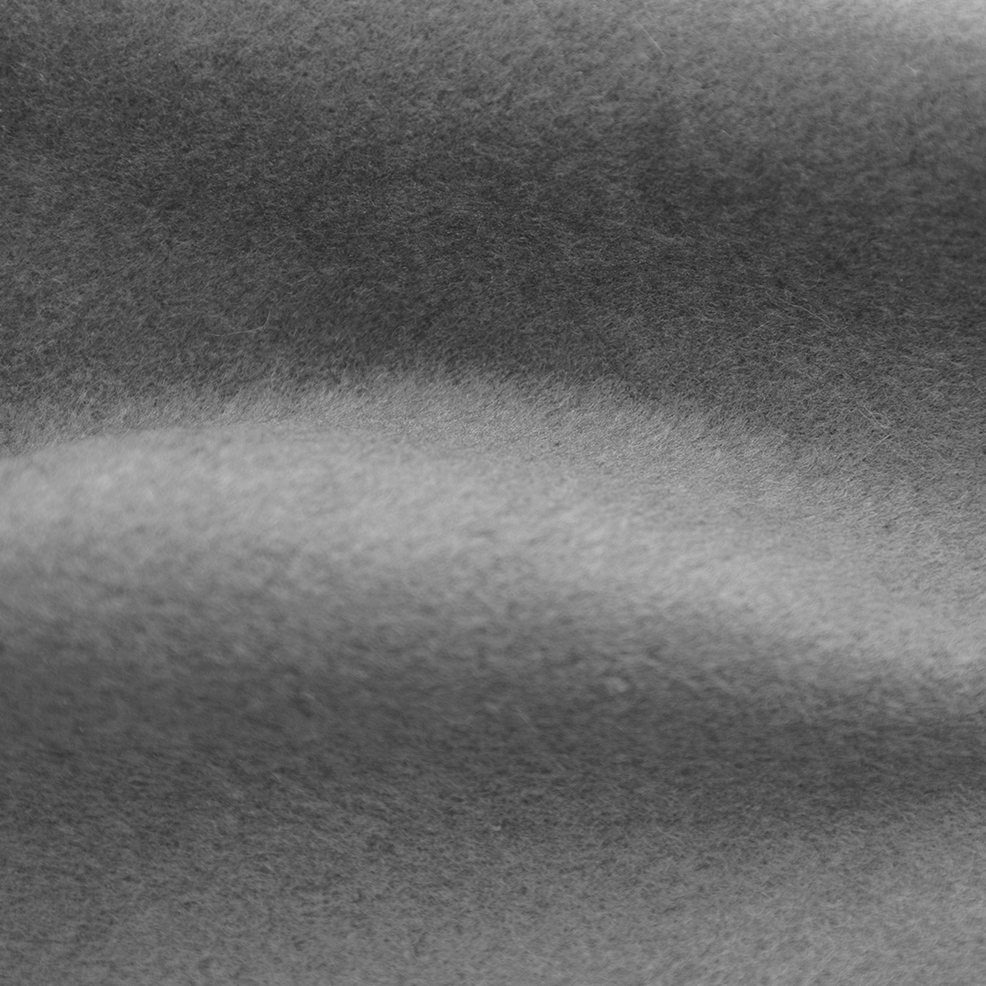Close-up van zachte, grijze viltstof. De textuur is enigszins ongelijkmatig, met subtiele toonvariaties.