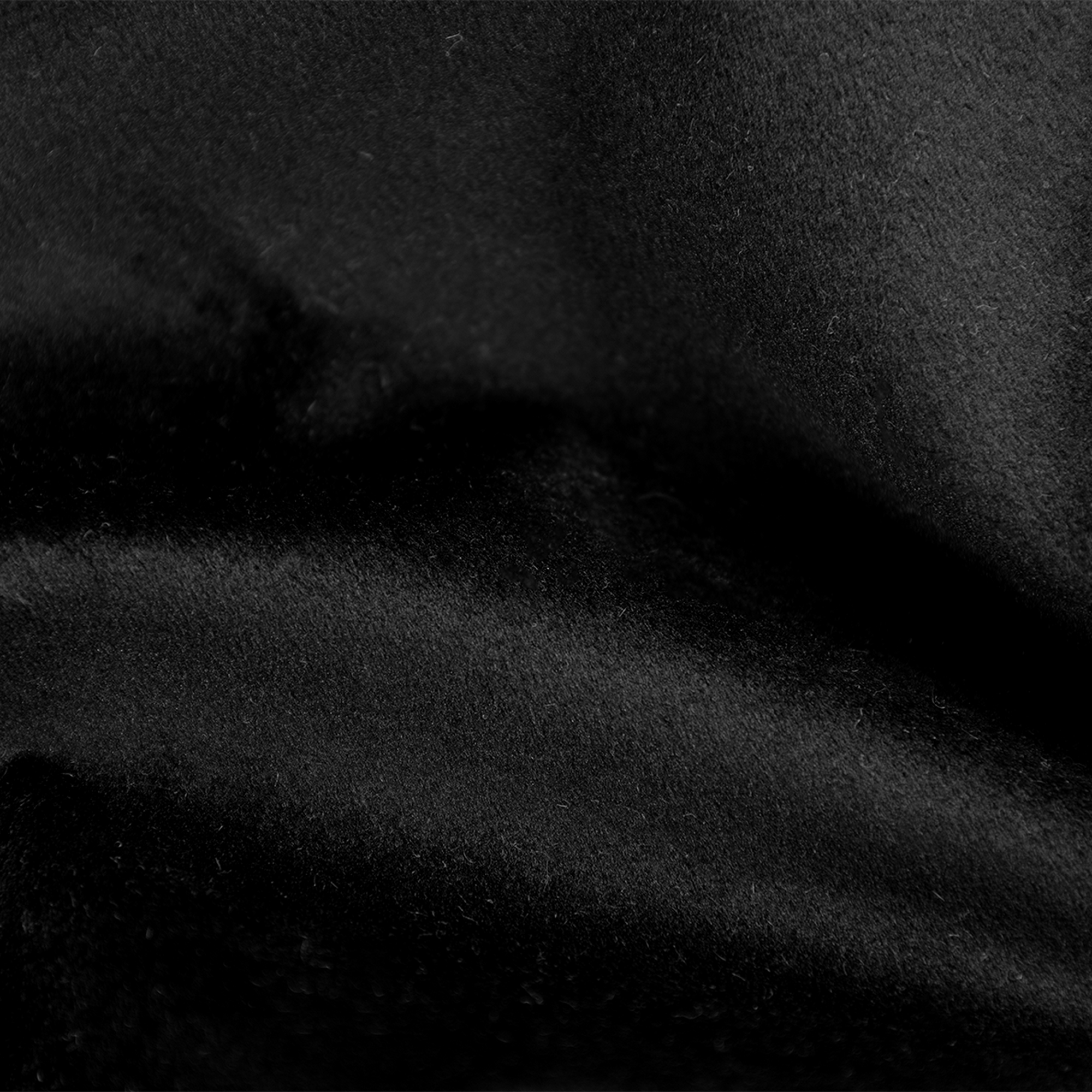 Close-up van zwarte stof. De textuur is zacht en licht golvend, met subtiele lichtreflecties.