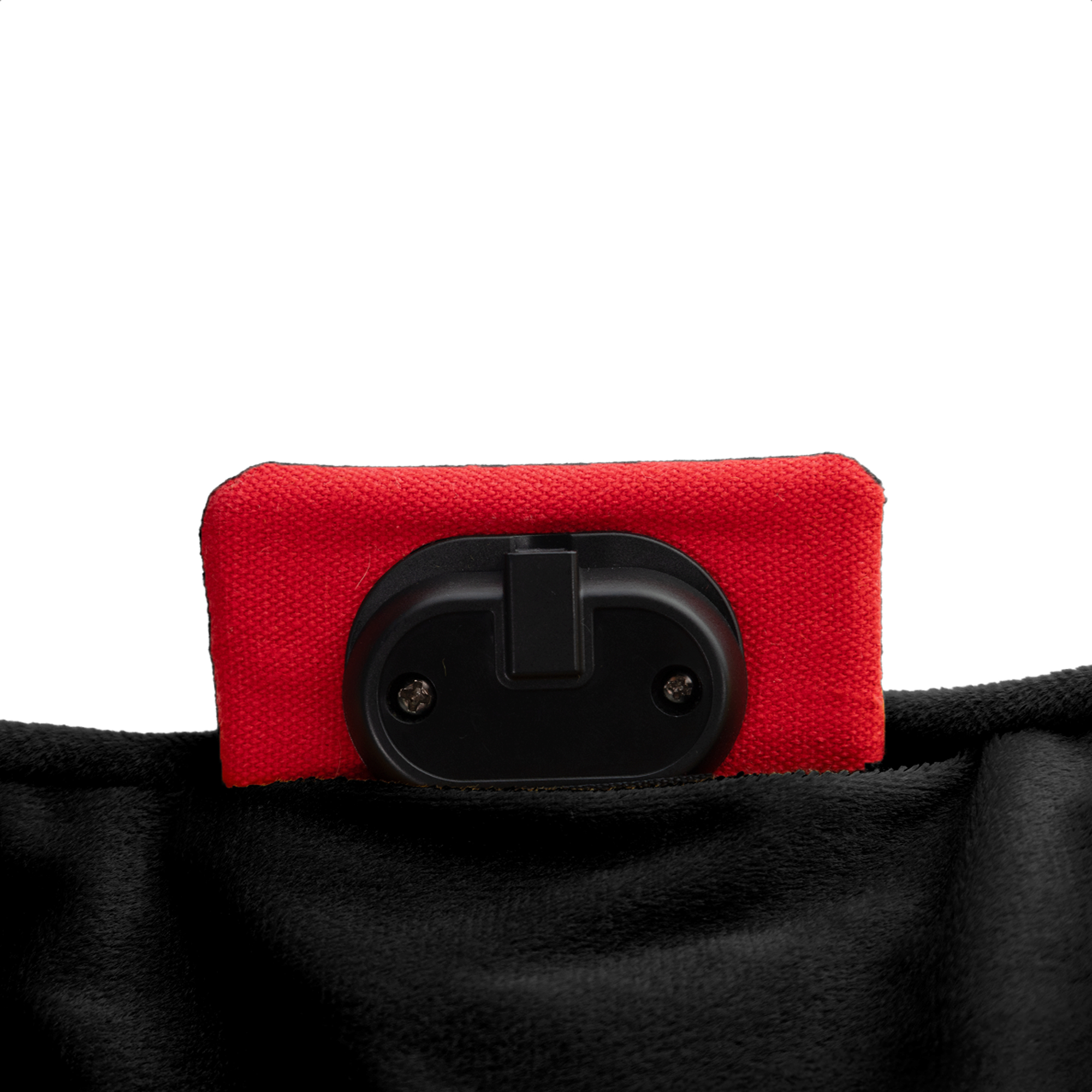 Een rood rechthoekig object met een zwart plastic onderdeel ligt op zwarte stof, tegen een witte achtergrond.