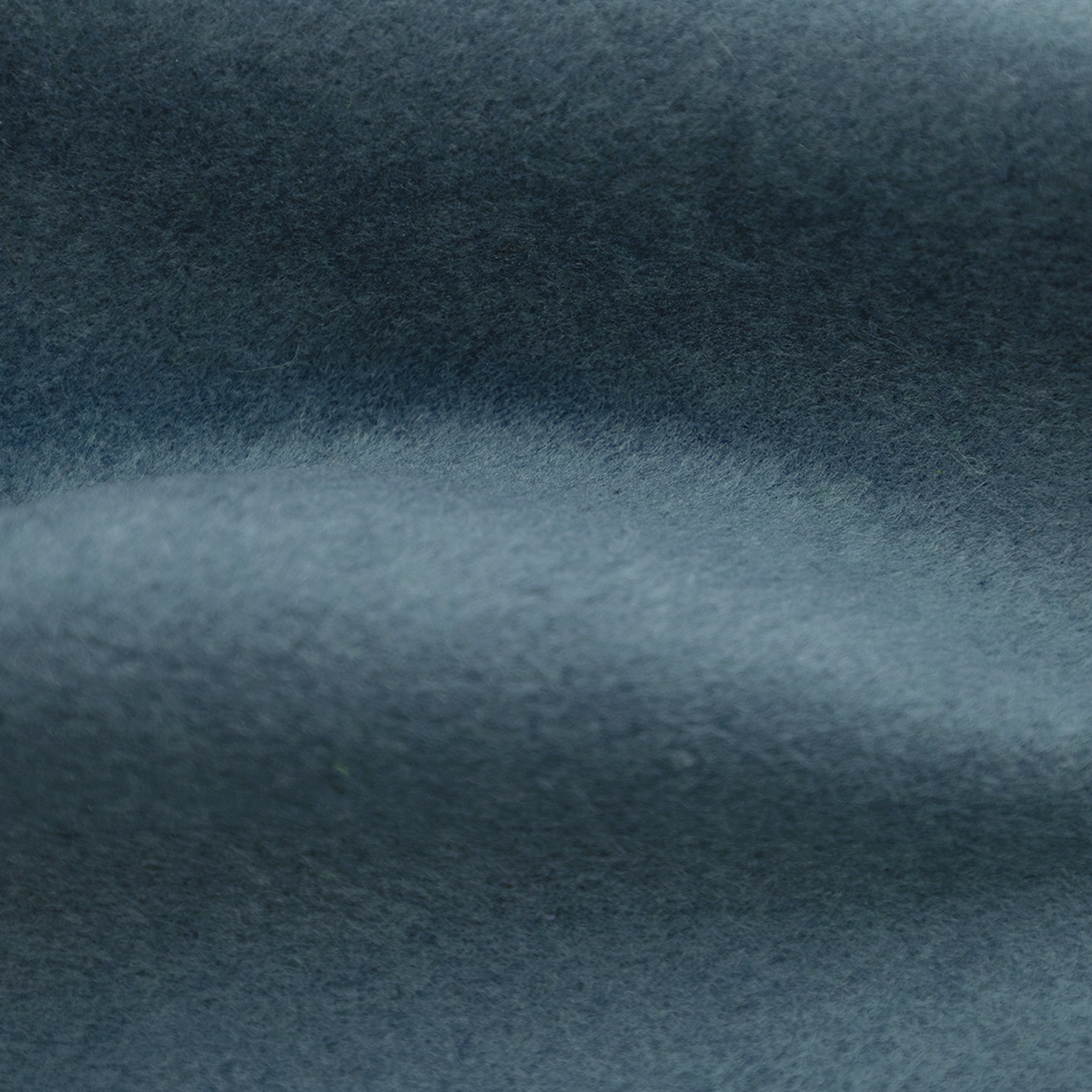 Close-up of a teal fabric. The texture is fuzzy, with soft shadows creating depth. The fabric appears smooth and clean.