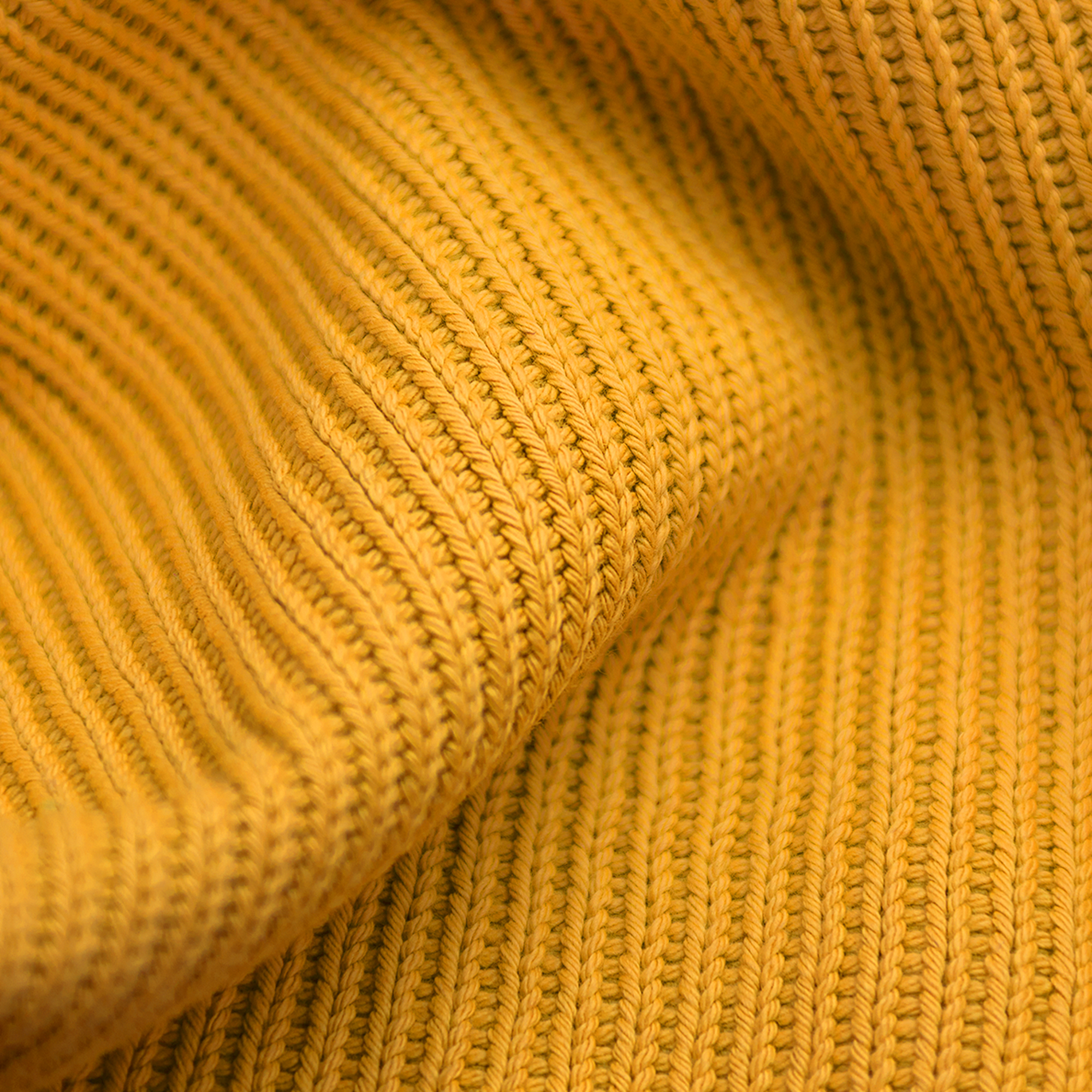 Gros plan sur un tissu en maille jaune avec une section pliée. La texture est visible. La lumière est douce et uniforme.