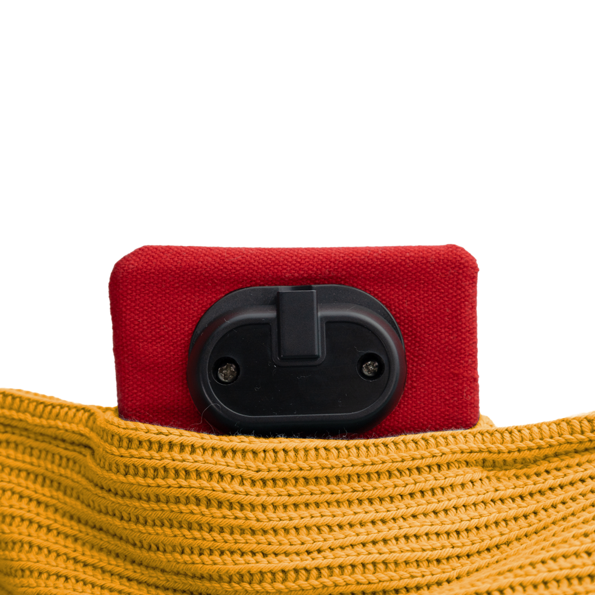 Un objet rouge avec un bouton noir est placé sur un tissu tricoté jaune. Fond blanc.