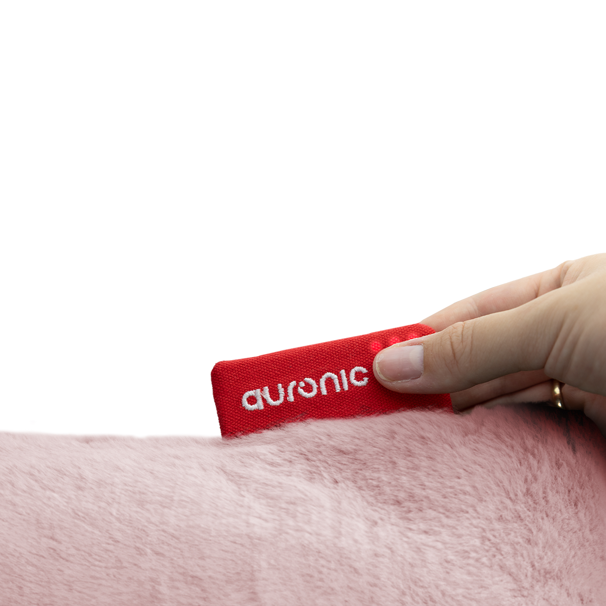 Une main tient une étiquette en tissu rouge avec 'auronic' sur une surface rose et duveteuse, sur fond blanc.