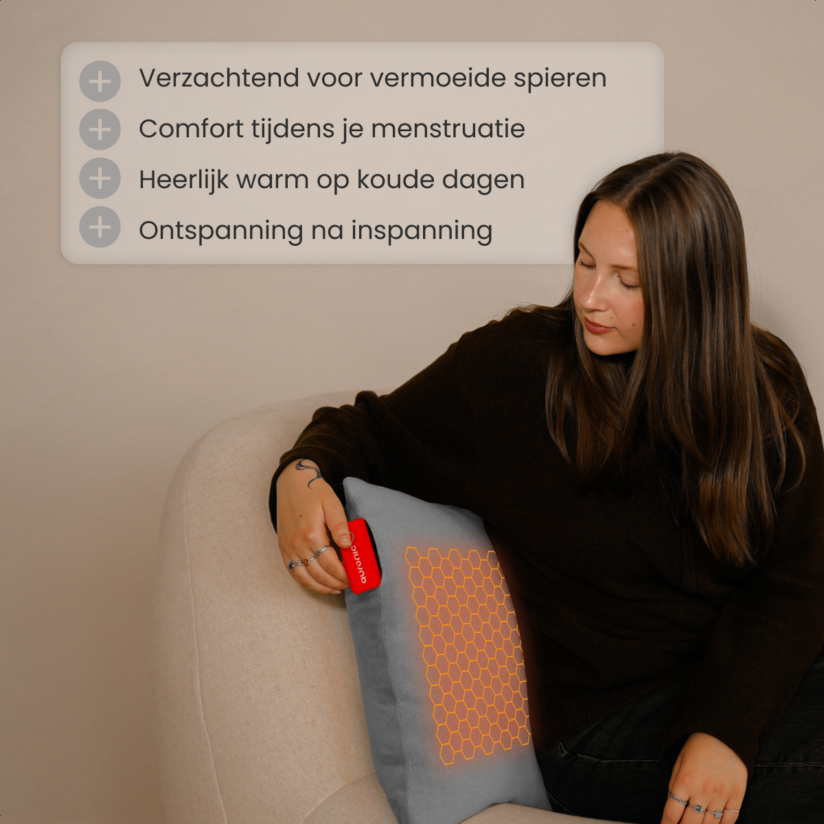 A woman in a black sweater holds a gray pillow with a red controller. The pillow has an orange honeycomb pattern.