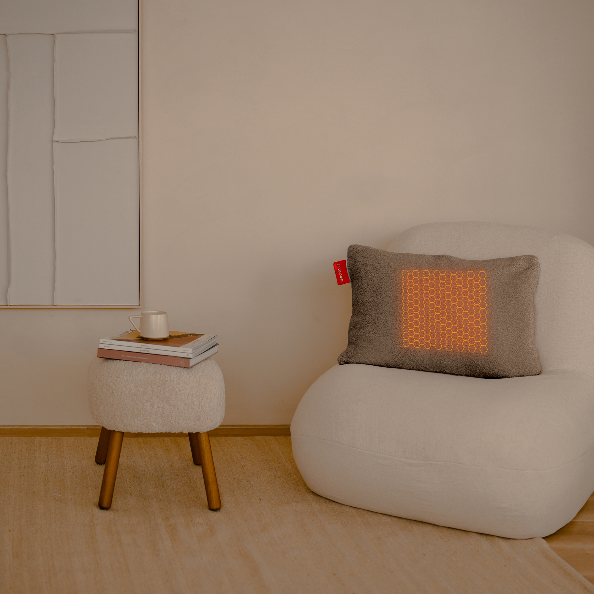 Un salon avec une chaise blanche, un oreiller avec coussin chauffant et une table d'appoint avec tasse et livres.