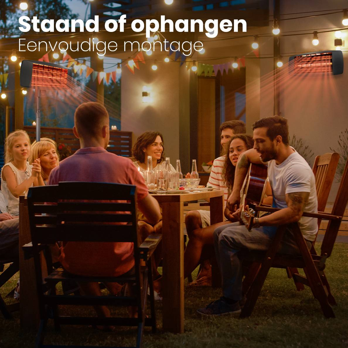 Eine Gruppe von Leuten sitzt abends im Freien um einen Tisch. Ein Mann spielt Gitarre, andere lächeln. Zwei Heizungen sind sichtbar.