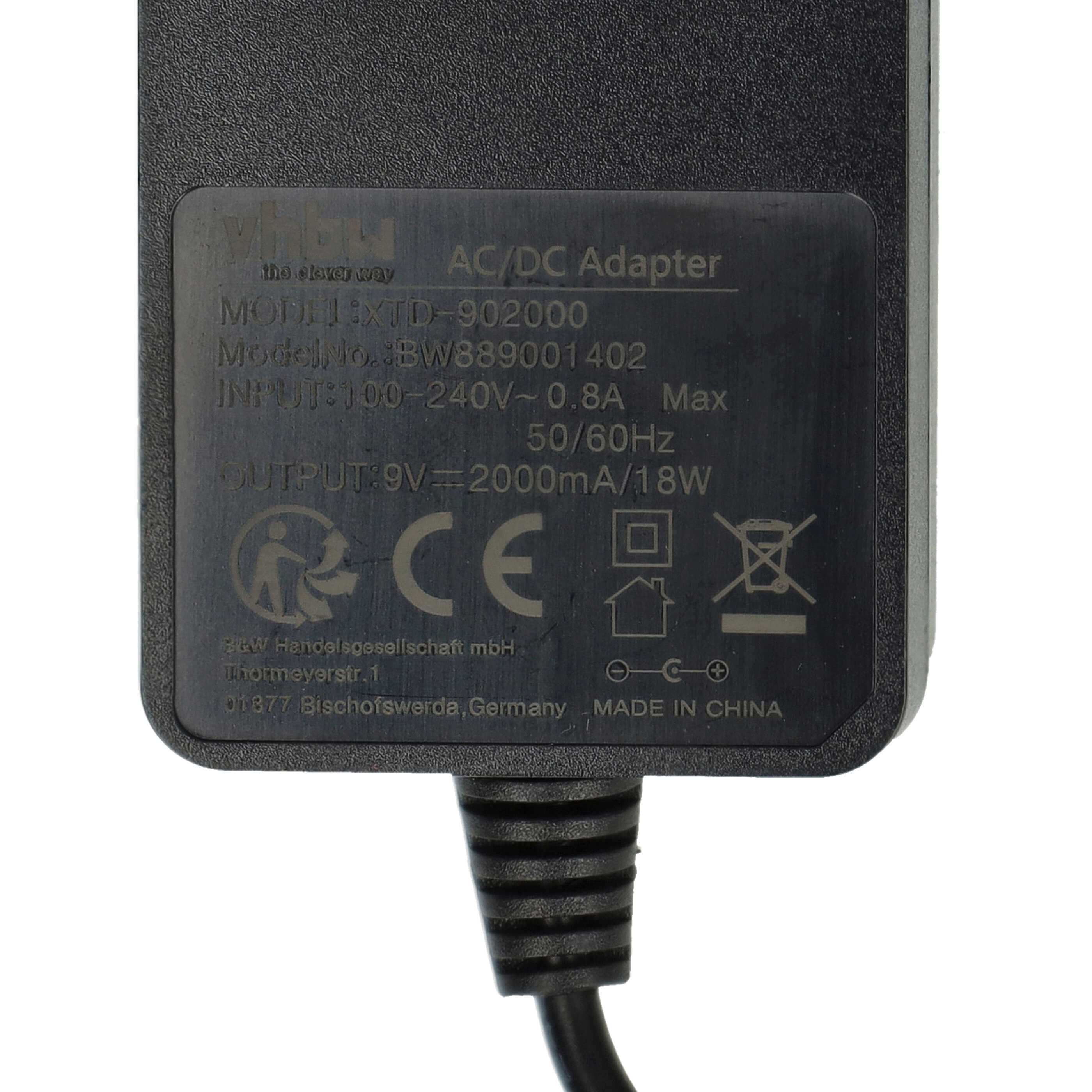 Schwarzer AC/DC-Adapter mit Modelldetails und Ausgangsspezifikationen auf der Oberfläche. Ein schwarzes Kabel erstreckt sich.