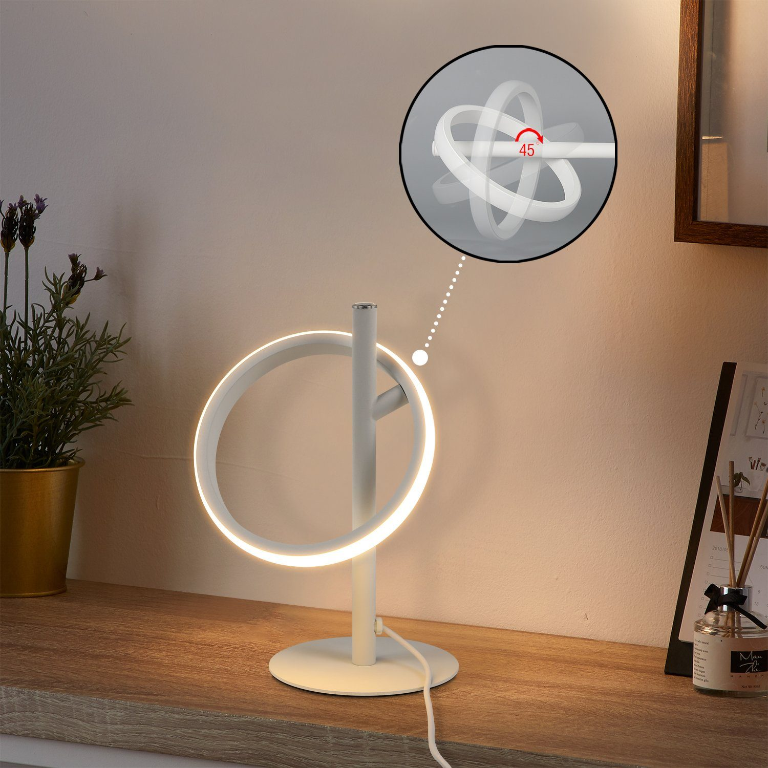 Una lámpara blanca en forma de anillo con soporte sobre una superficie de madera. Un diagrama muestra el ángulo de rotación. Planta y calendario a los lados.