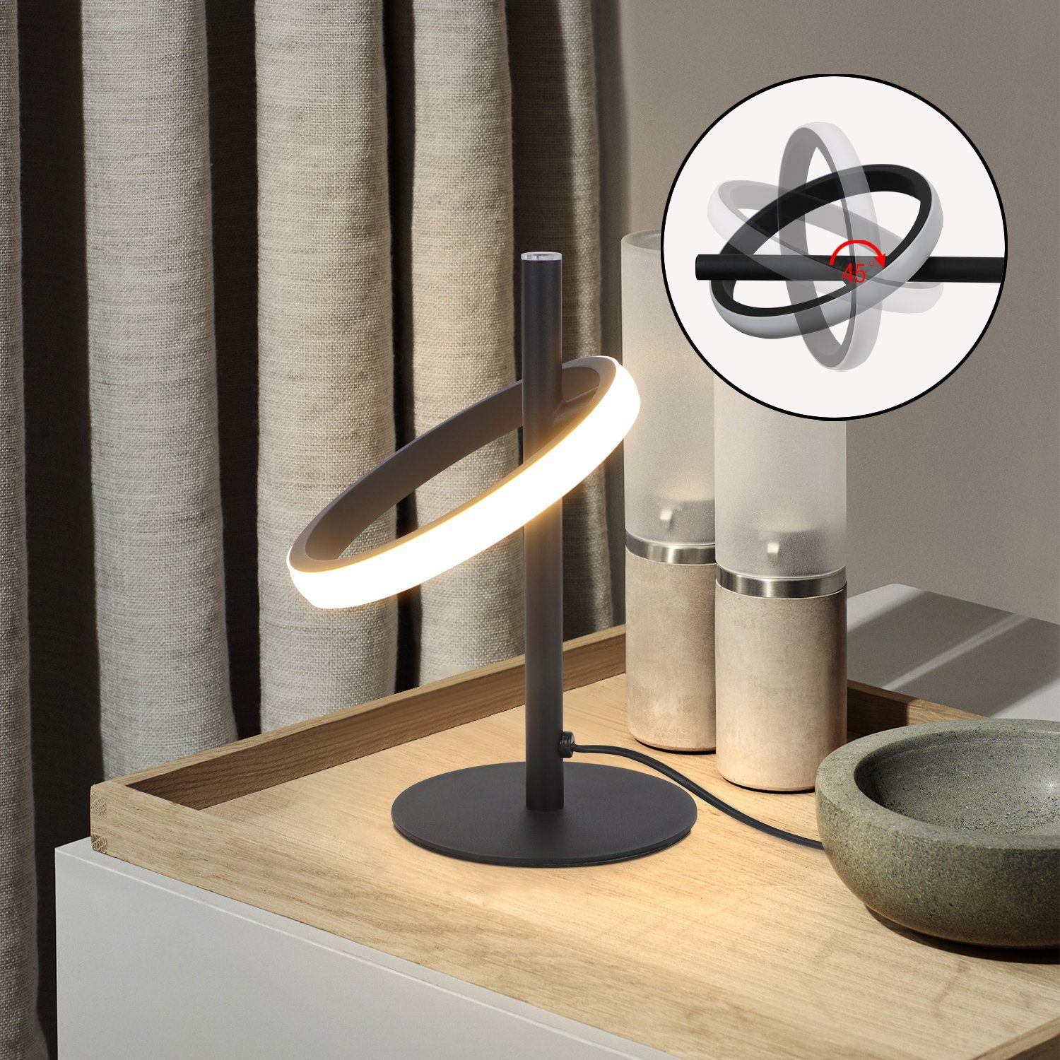 Una lámpara negra moderna con luz circular. Está sobre una bandeja de madera con otros objetos. Un diagrama muestra la rotación de la luz.