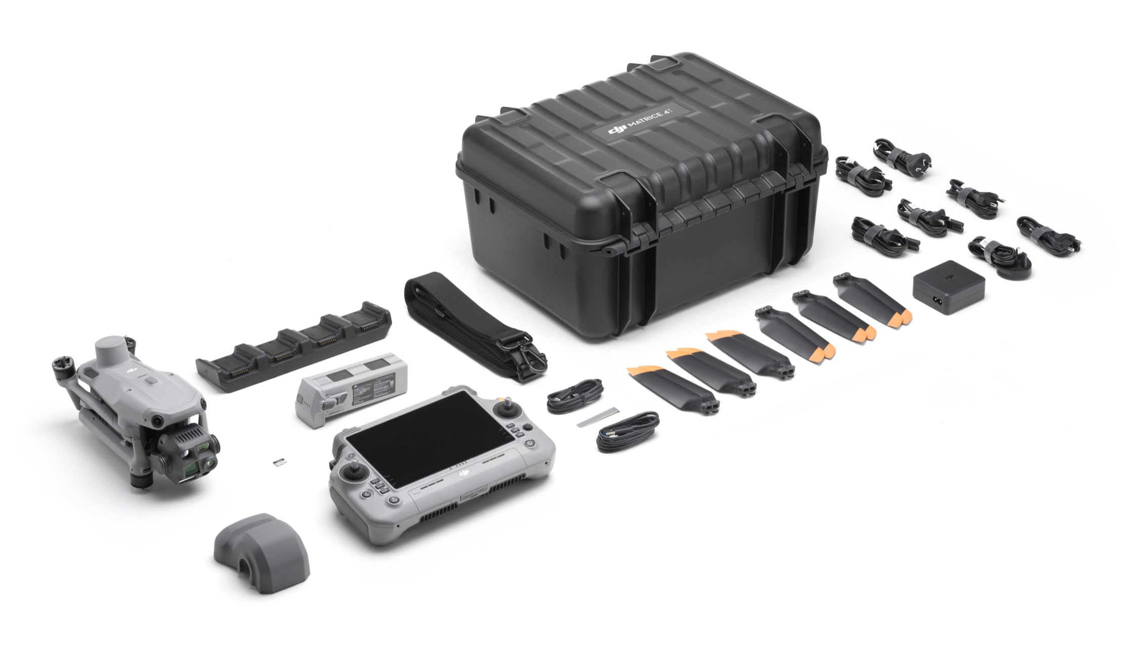 Un kit drone su una superficie bianca. Include drone, telecomando, custodia, caricatore, batterie, eliche, cavi e accessori.