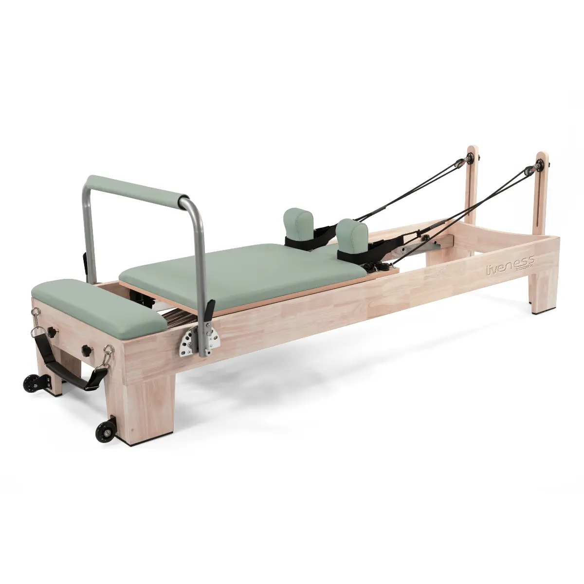 Een Pilates reformer-machine. Het heeft een licht houten frame, groene vulling en zwarte banden. Het staat op wielen.