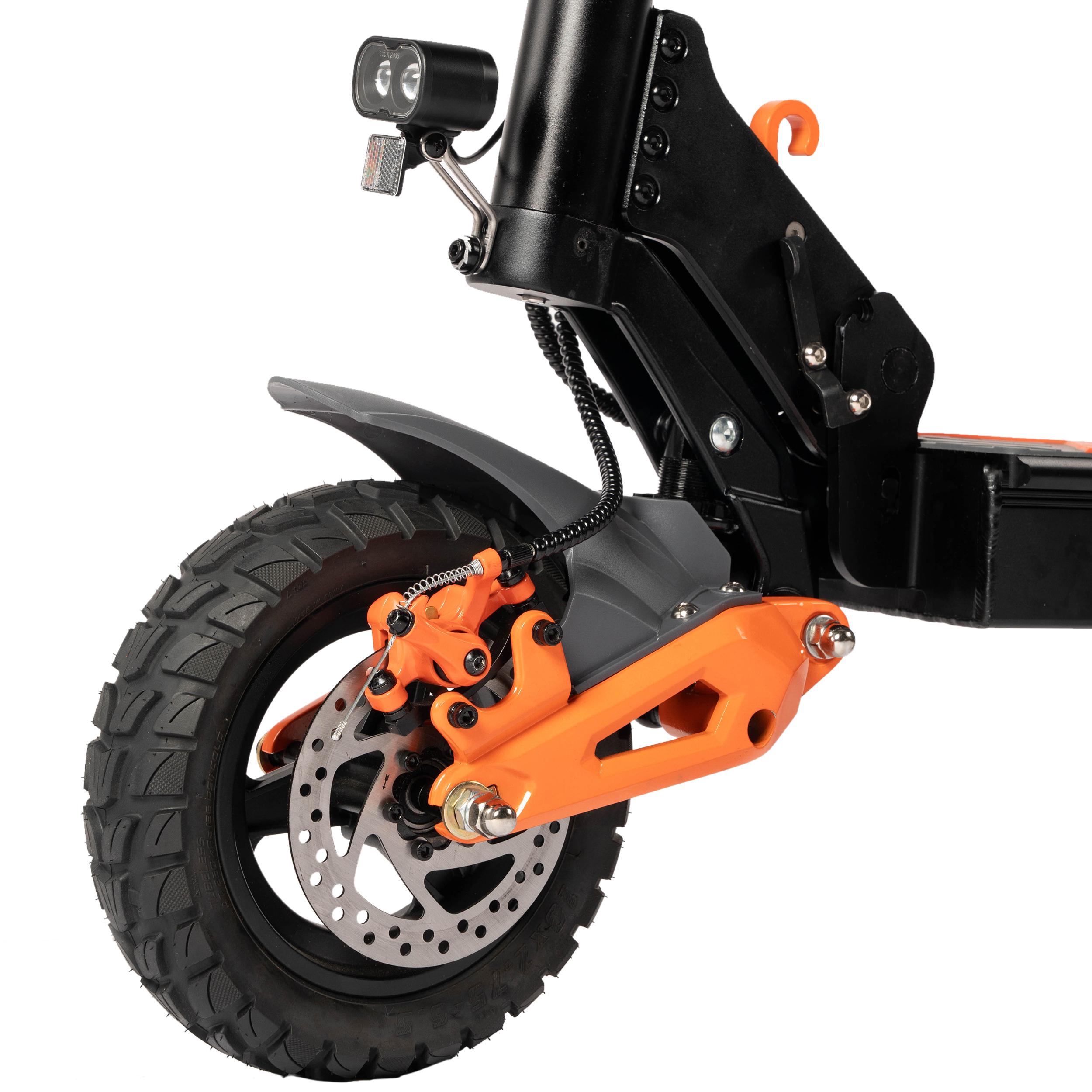 Zbliżenie przedniego koła hulajnogi elektrycznej. Czarna opona, pomarańczowe elementy hamulców i widoczny reflektor.