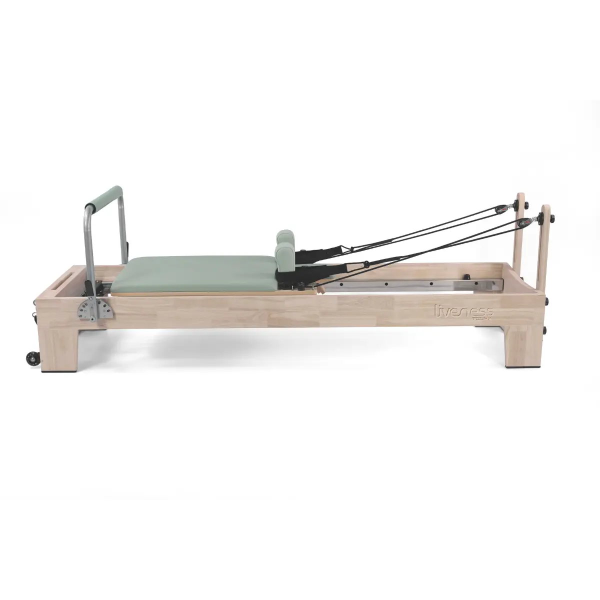 Een lichte Pilates reformer van hout met groene vulling, zwarte banden en een metalen frame op een witte achtergrond.