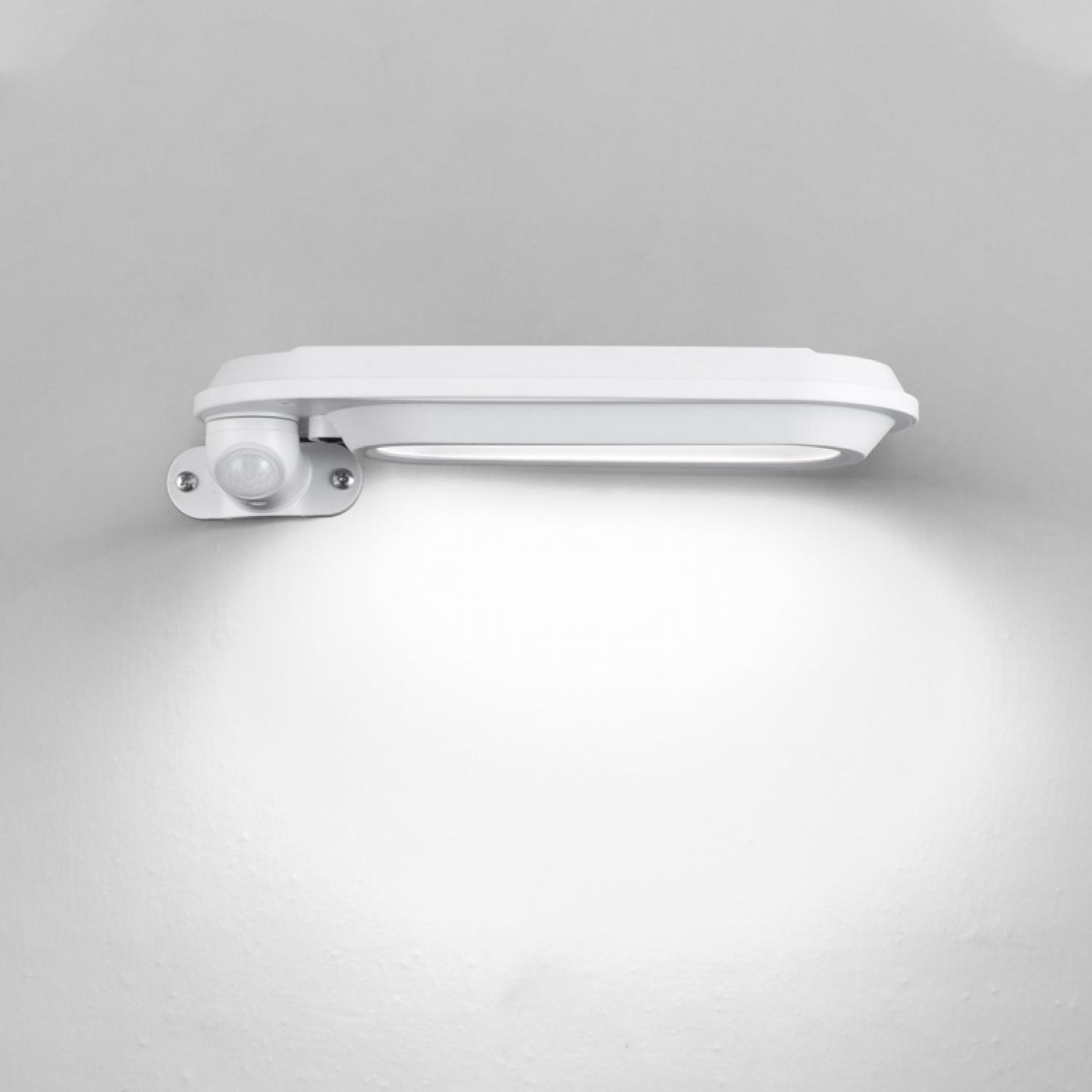 Weißes, an der Wand montiertes LED-Licht mit Bewegungssensor. Das Licht ist an und wirft einen hellen Kreis auf die Wand darunter.