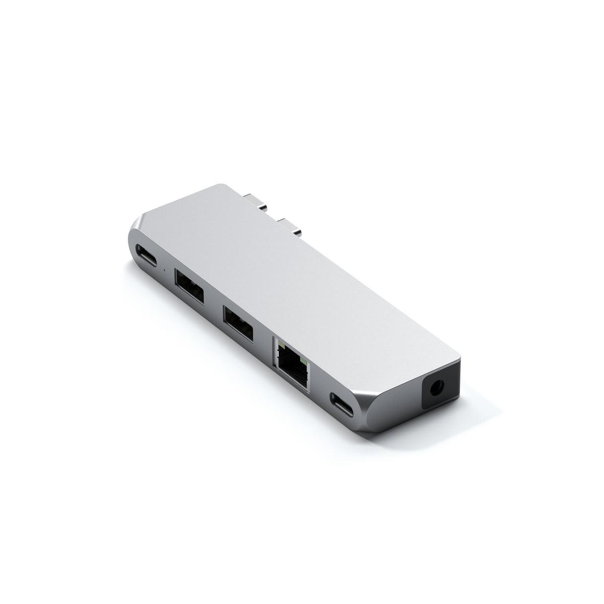 Ein silberner USB-C-Hub mit mehreren Anschlüssen, darunter USB, Ethernet und Ladeanschlüsse, liegt auf weißem Untergrund.