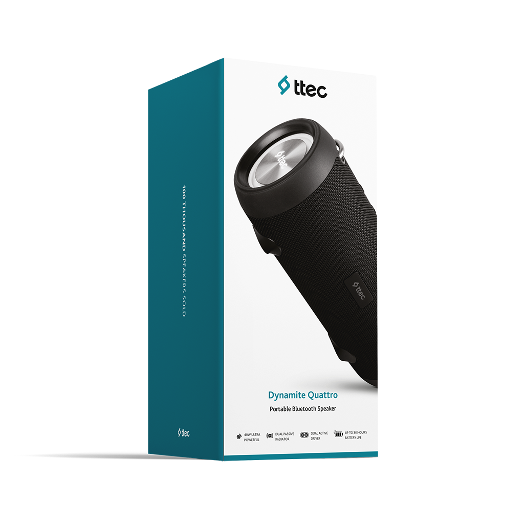 Sağa doğru eğilmiş siyah bir taşınabilir Bluetooth hoparlör. Gümüş bir üst kısmı vardır ve marka adı ttec'tir. Kutuda Dynamite Quattro yazıyor.