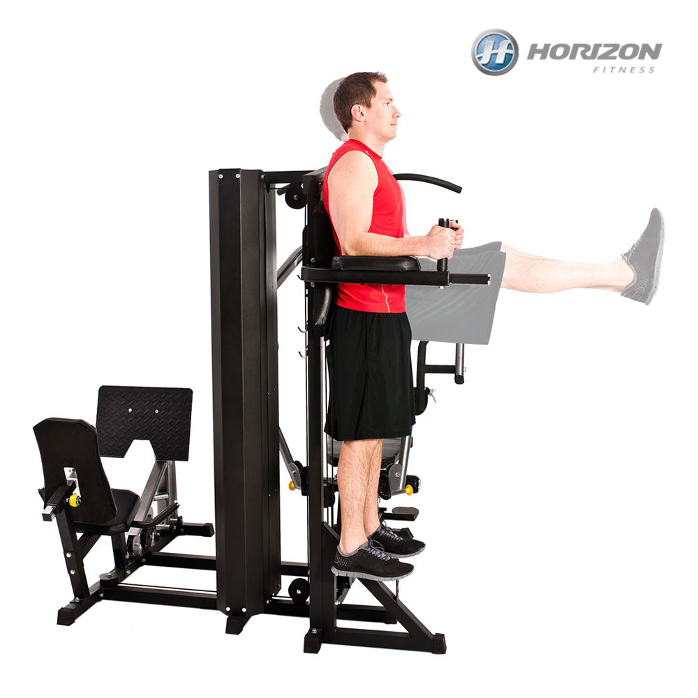 Adam egzersiz makinesi kullanıyor. Kırmızı bir gömlek ve siyah şort giyiyor. Makine siyah. Horizon Fitness logosu görünür.