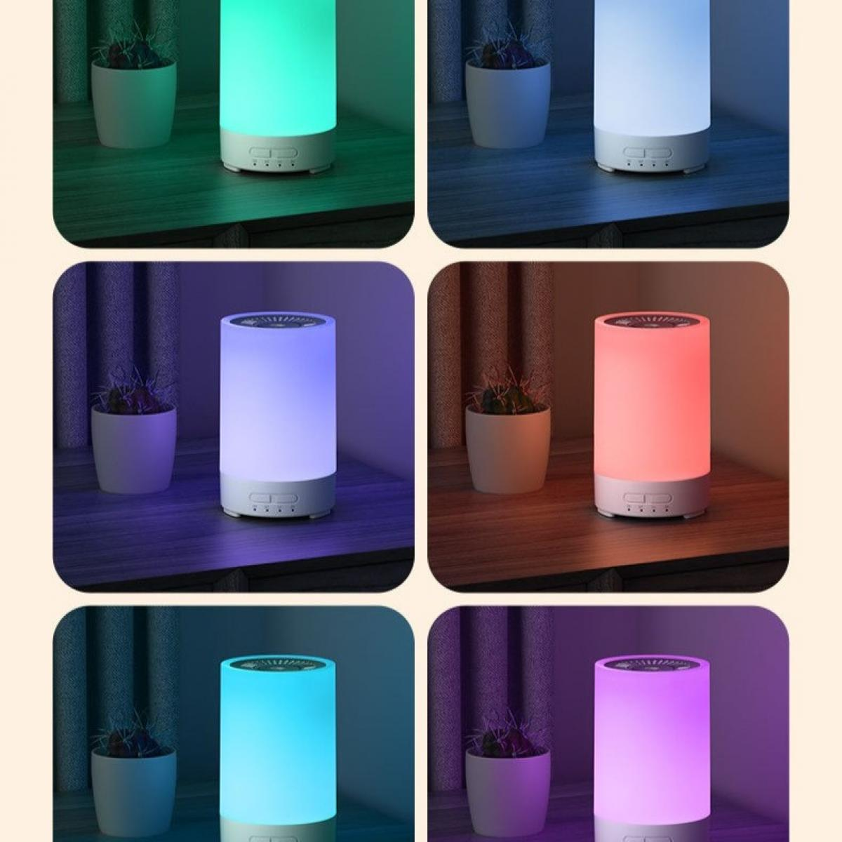 Das Bild zeigt eine zylindrische Lampe mit Farbvariationen wie Grün, Blau, Rot und Lila, mit kleinen Topfpflanzen im Hintergrund.