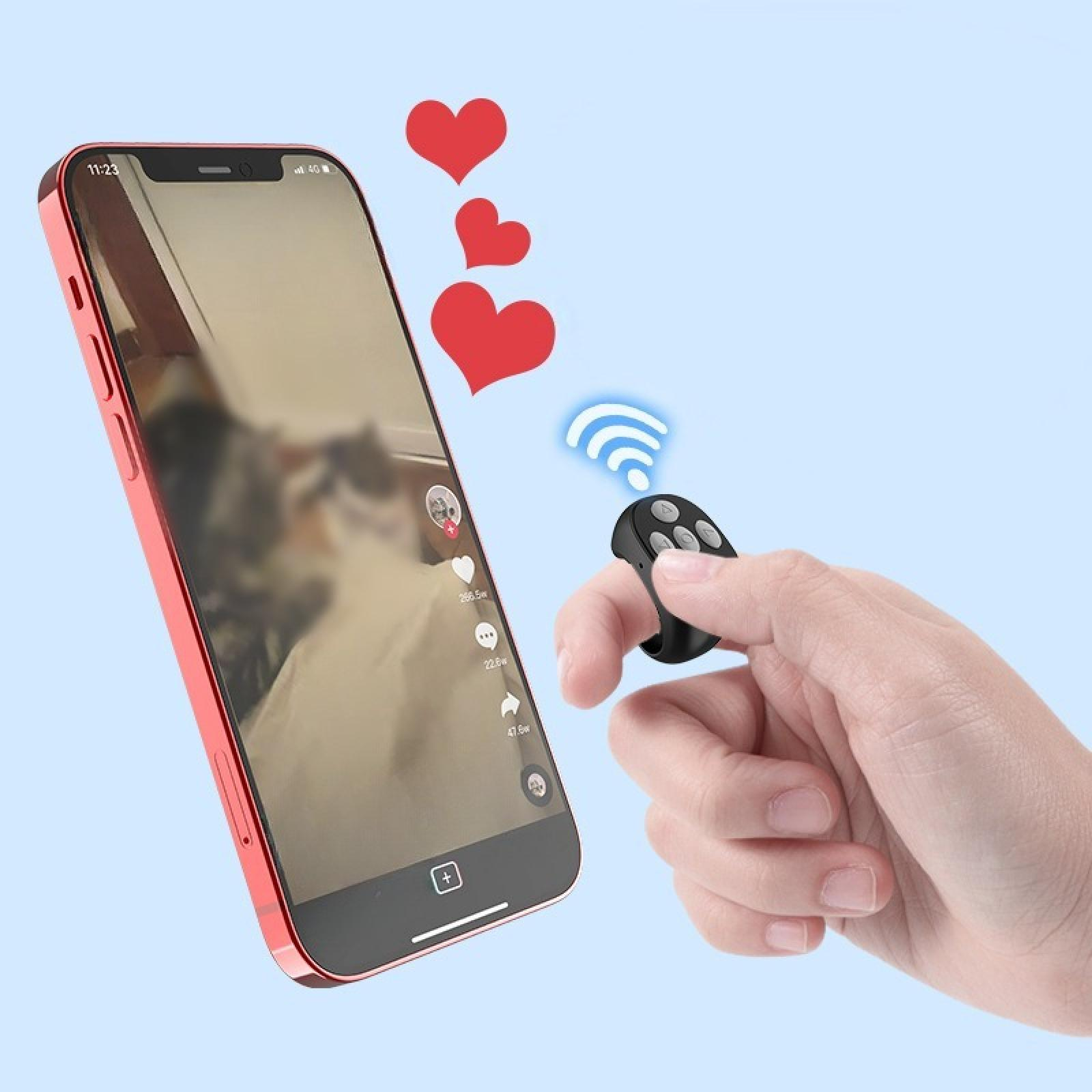 Eine Hand hält eine Fernbedienung. Ein Telefon zeigt ein Video mit roten Herzen und einem 4G-Signal.