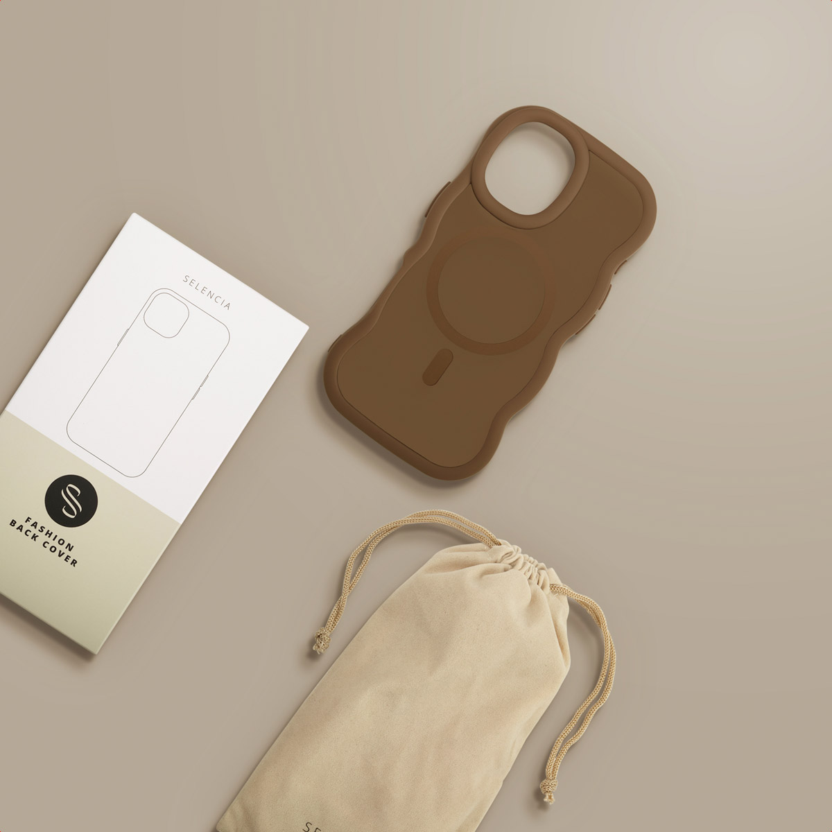Een bruine telefoonhoes, een witte doos met een telefooncontour en een beige tas liggen op een beige oppervlak.