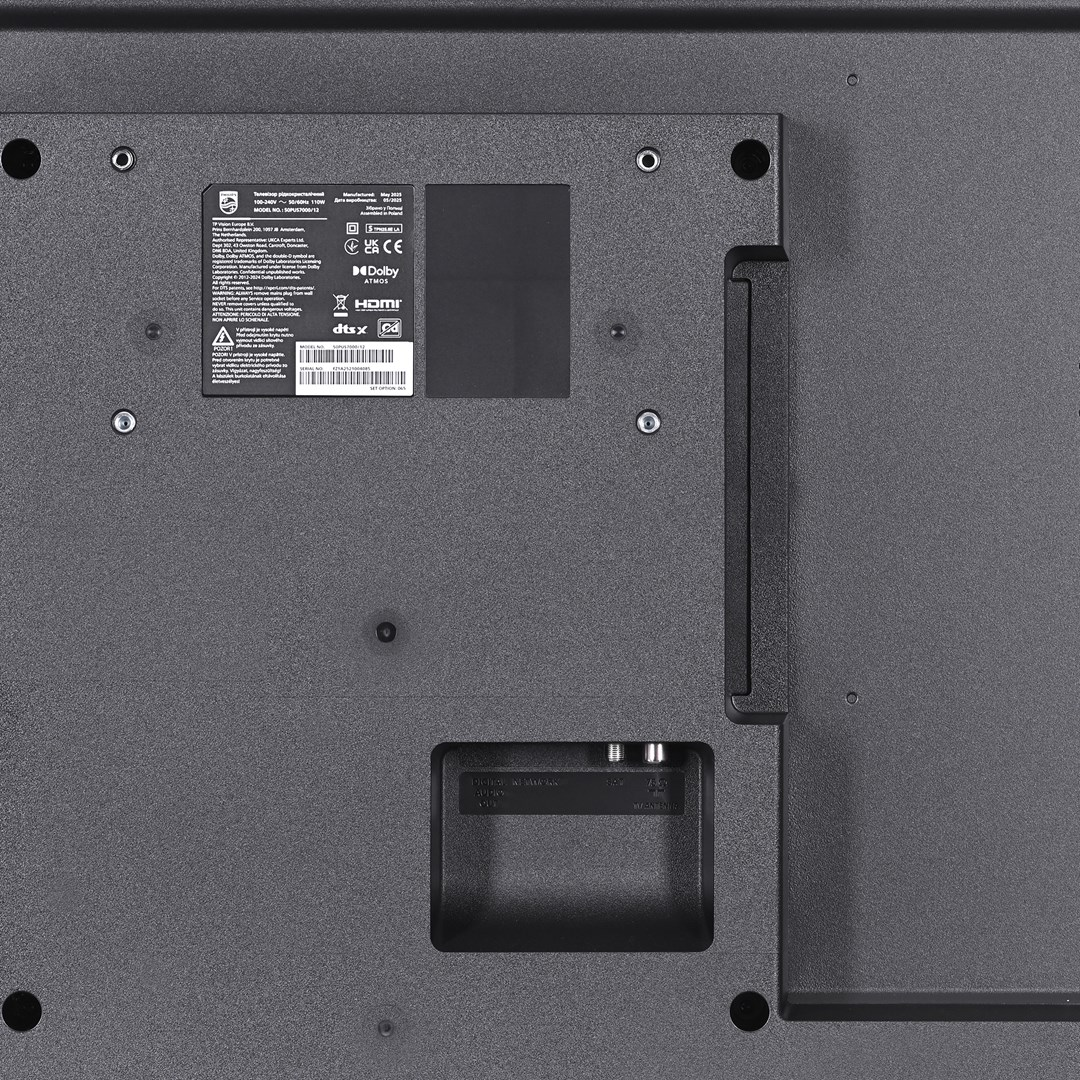 Zbliżenie szarego tyłu telewizora. Widoczne są różne etykiety, porty i otwory montażowe.
