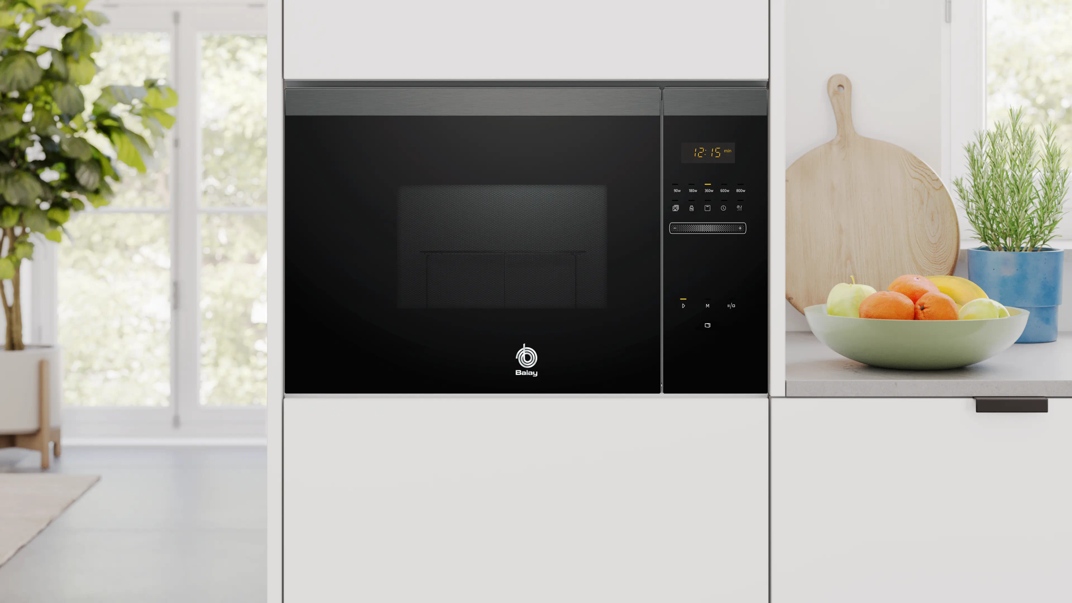 Czarna kuchenka mikrofalowa z cyfrowym zegarem jest wyśrodkowana. Miska owoców znajduje się po prawej stronie. Widoczna jest również roślina i drewniana deska do krojenia.