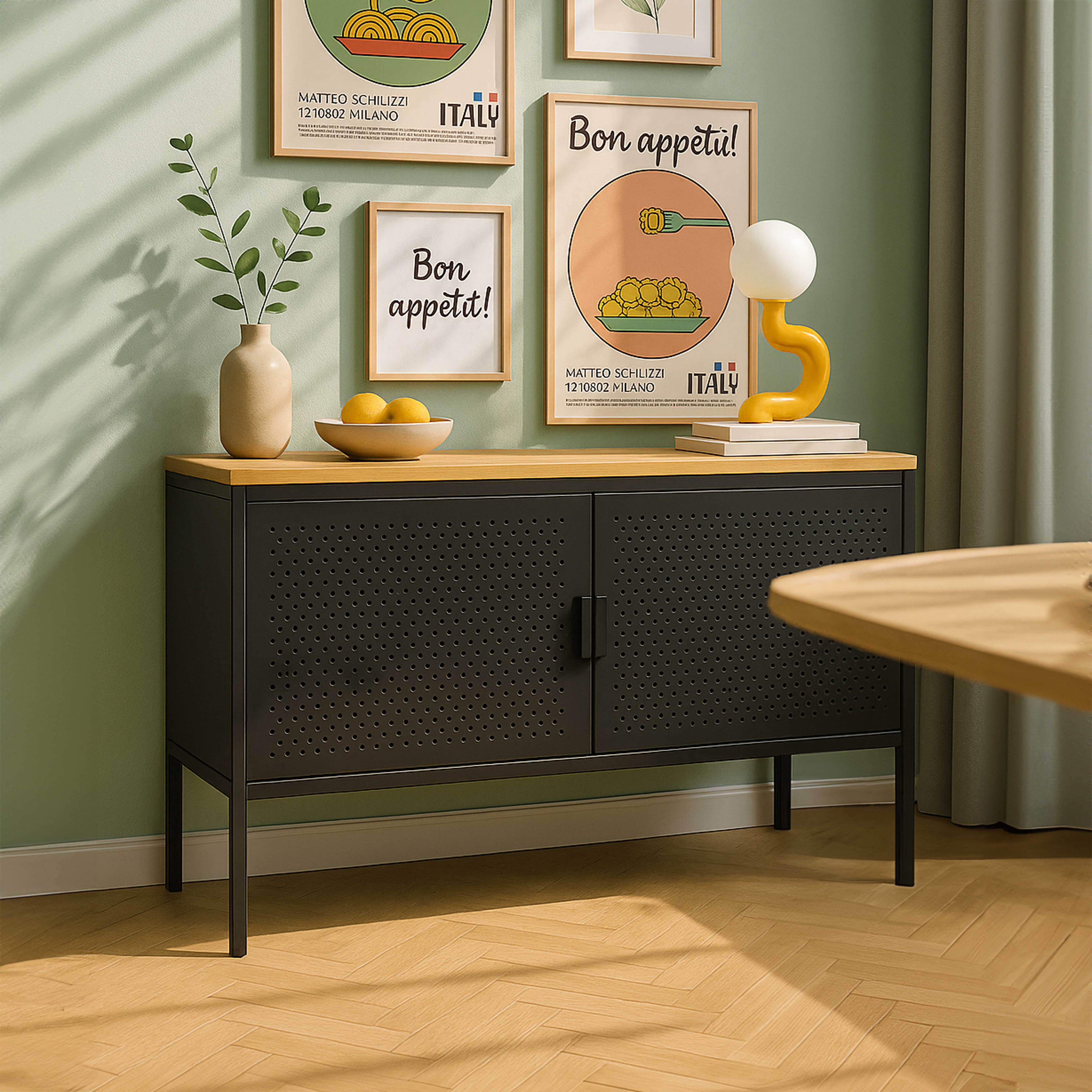 Ein Schrank mit Dekoration, Postern und einer Lampe. Die Wand ist grün. Im Vordergrund ein Holztisch.