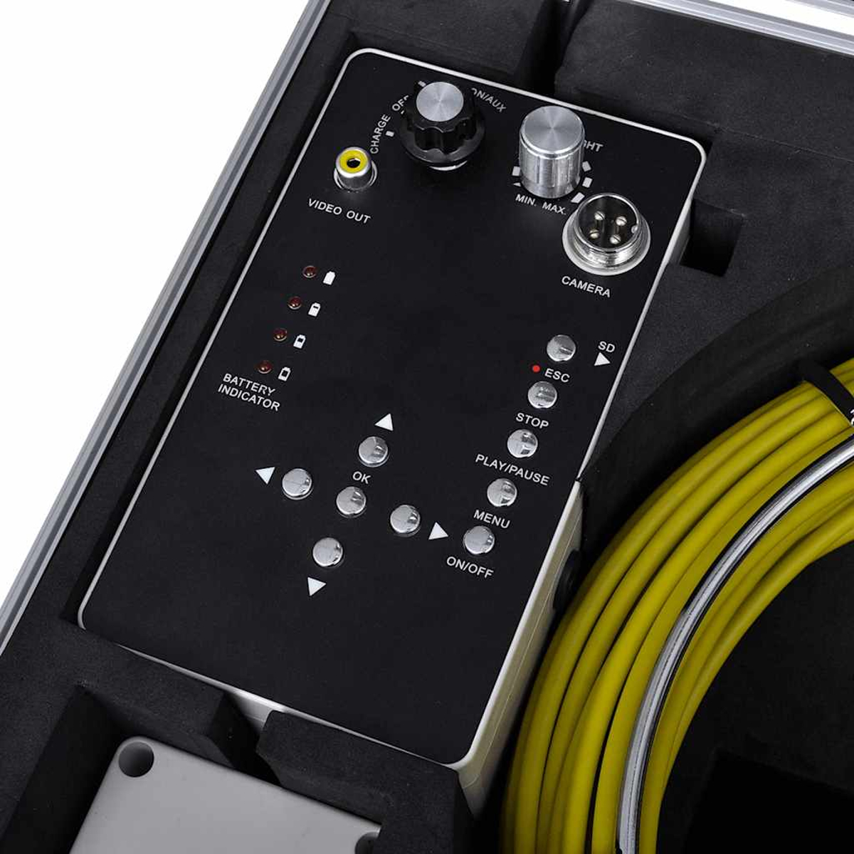 Eine schwarze Steuerungstafel mit Knöpfen und Drehreglern, beschriftet mit 'Video Out', 'Camera' und 'Battery Indicator', mit einem gelben Kabel.