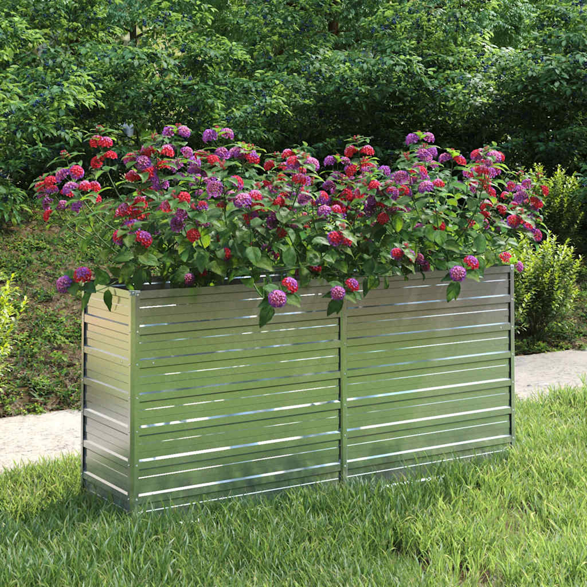 Ein Metallpflanzer mit bunten Blumen steht auf Gras. Bäume bilden den Hintergrund. Die Blumen sind rot, lila und rosa.