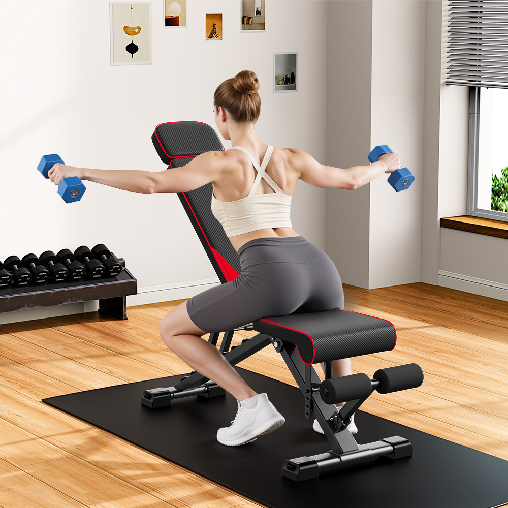 Kobieta ćwiczy na ławce, trzymając hantle. W tle stojak na hantle i sztuka na ścianie.