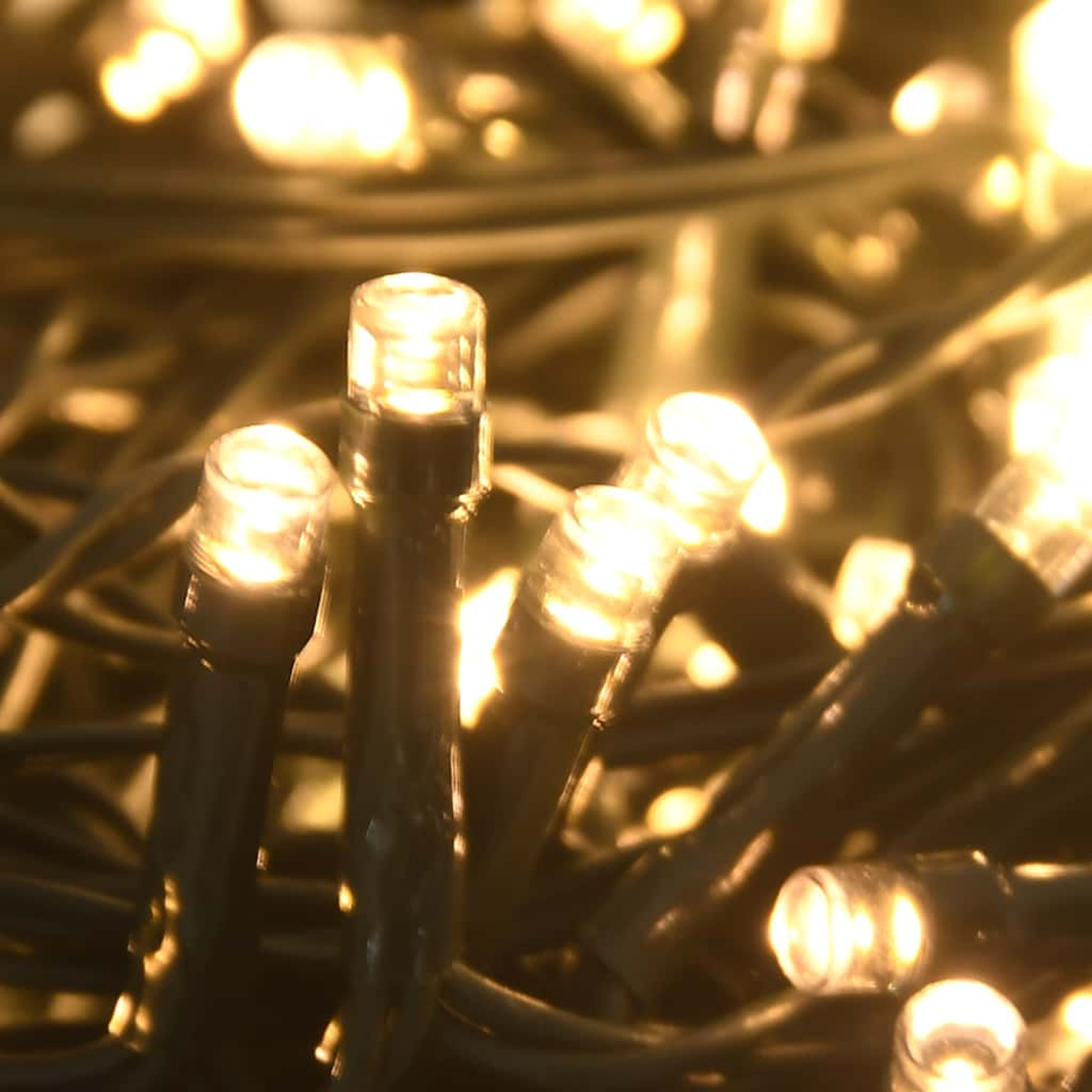 Nahaufnahme von warmweißen LED-Lichterketten. Einige Lichter sind fokussiert, andere verschwommen. Dunkelgrüner Draht ist sichtbar.