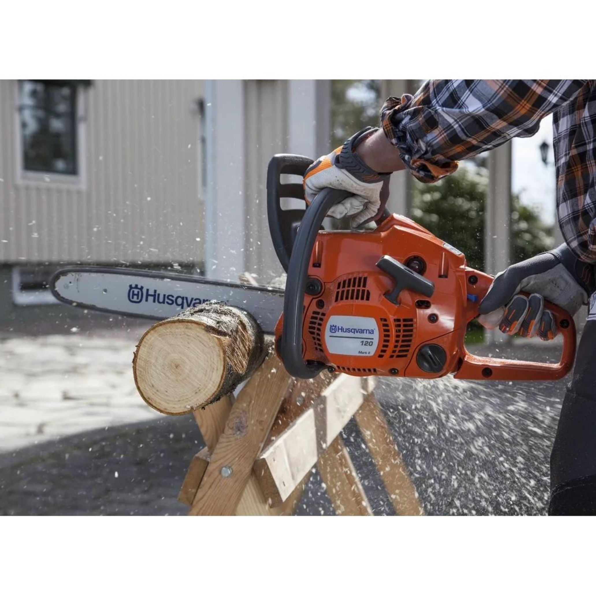 Bir kişi bir kütüğü kesmek için bir motorlu testere kullanıyor. Talaş havada uçuşuyor. Husqvarna logolu turuncu motorlu testere.
