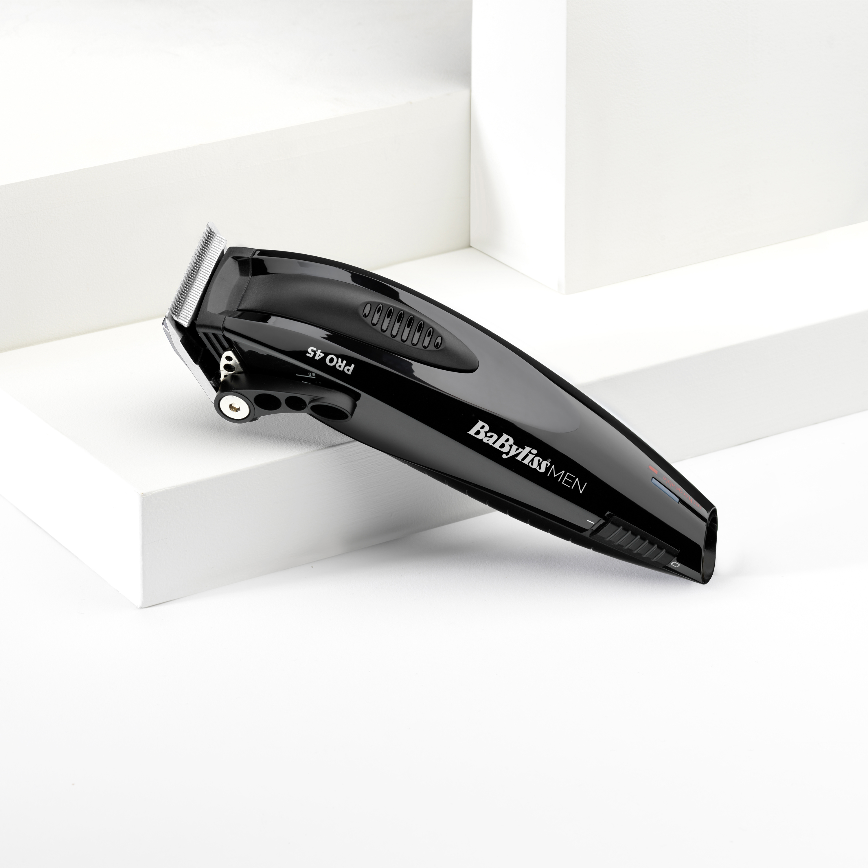 Un tagliacapelli Babyliss nero, PRO 45, su sfondo geometrico bianco. Il tagliacapelli è angolato.