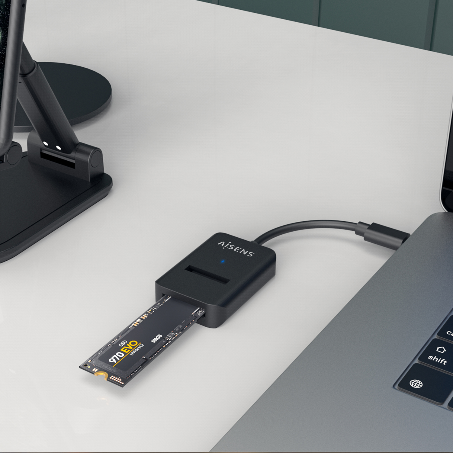 Una tarjeta SSD está conectada a una laptop con un adaptador negro. La SSD está parcialmente insertada en el adaptador, con la marca visible.