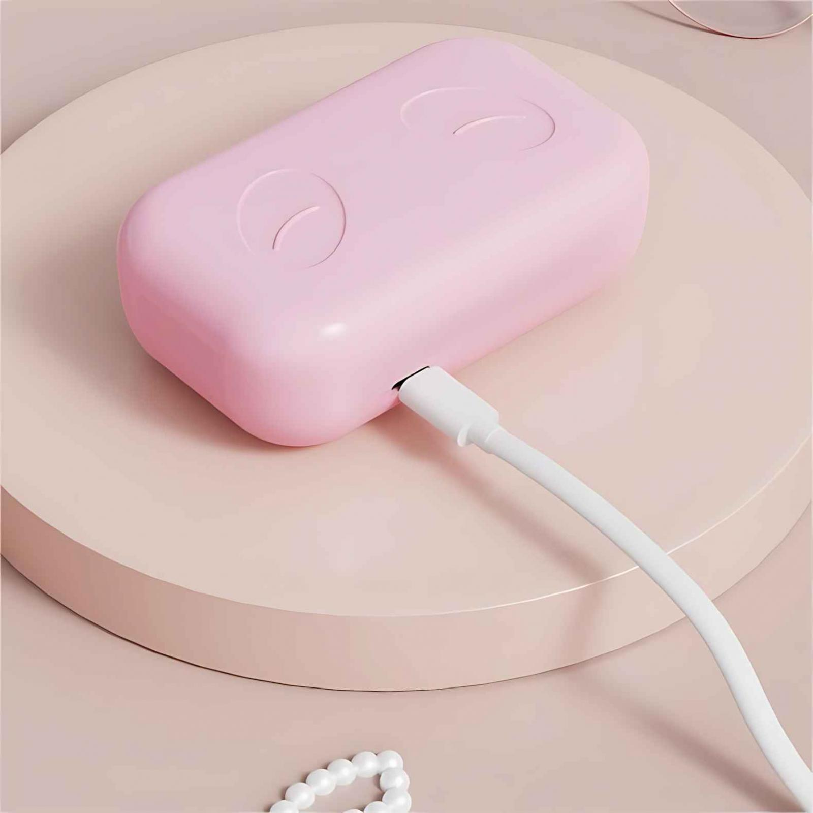 Ein rosa rechteckiges Gerät mit zwei gebogenen Linien. Ein weißes Kabel ist eingesteckt, das auf einer rosa Plattform liegt.