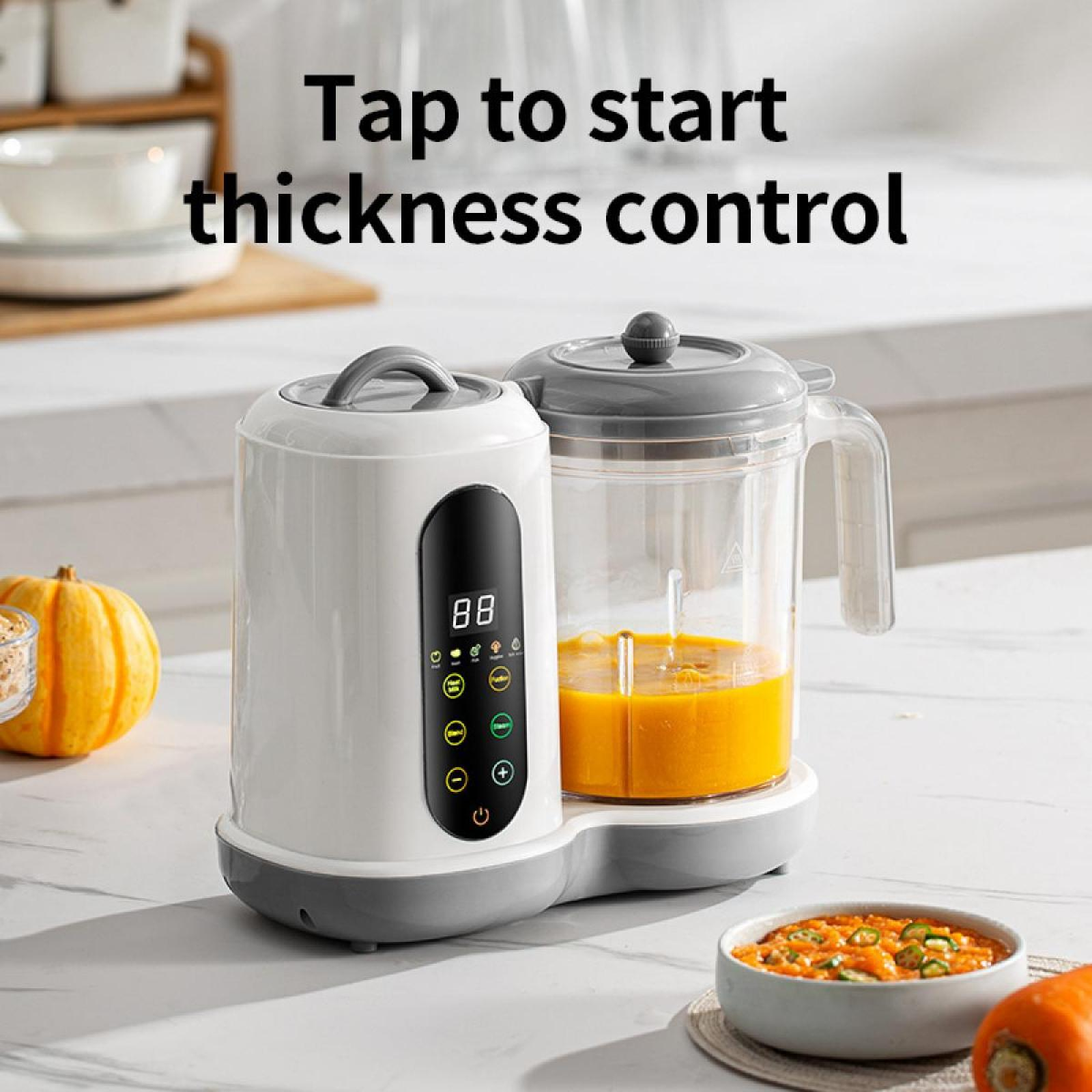 Ein weißer und grauer Foodprocessor mit orangener Flüssigkeit im Behälter. Eine Schüssel mit Essen und ein Kürbis stehen daneben.