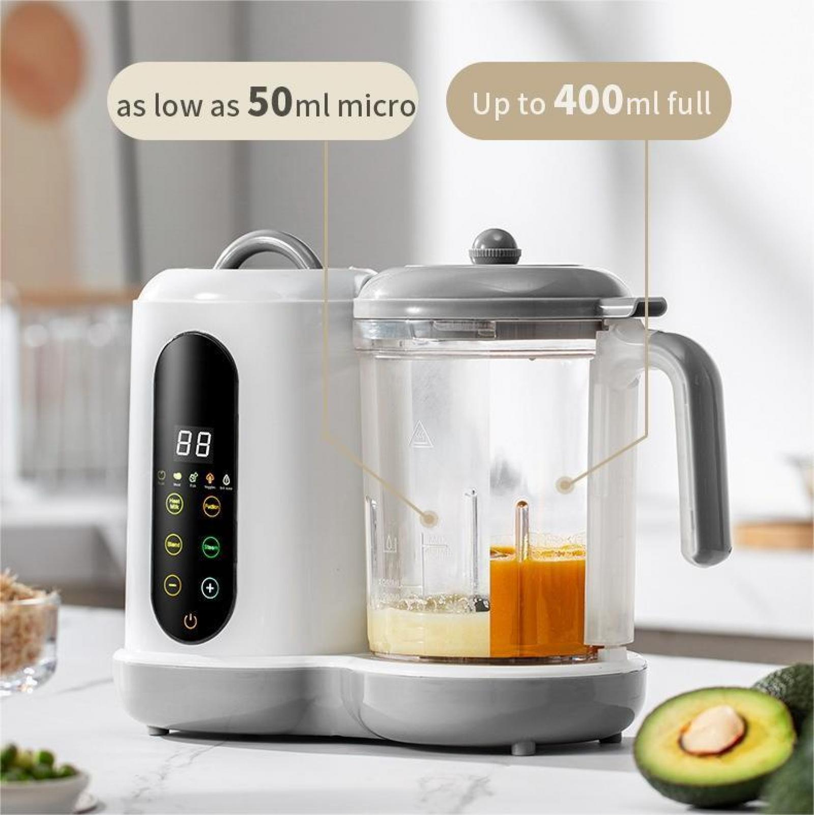 Ein weiß-grauer Babynahrungsbereiter mit einem transparenten Behälter, der Lebensmittel enthält. Das Bild zeigt auch eine Avocado.