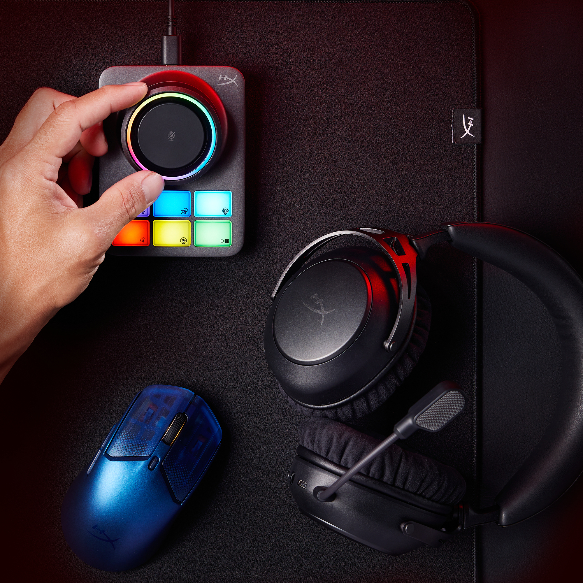 Dłoń reguluje panel sterowania z kolorowymi przyciskami. Zawiera niebieską mysz i czarne słuchawki na czarnej powierzchni.