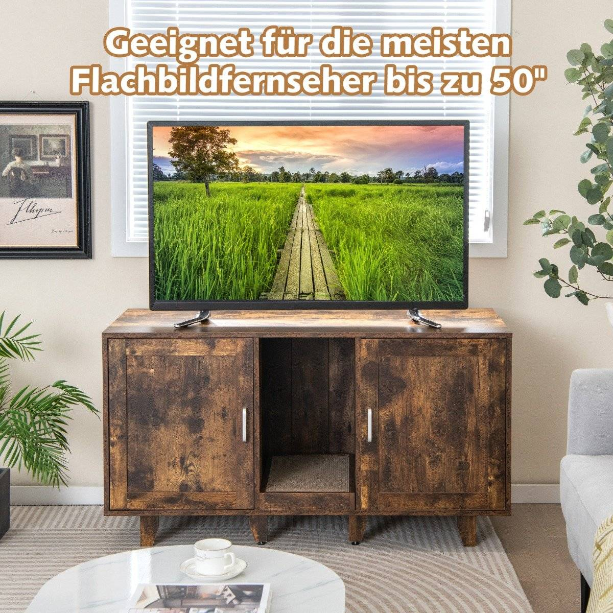 Un televisor está sobre un mueble de madera con una escena de paisaje en la pantalla. Una ventana está detrás del televisor y una imagen cuelga en la pared.