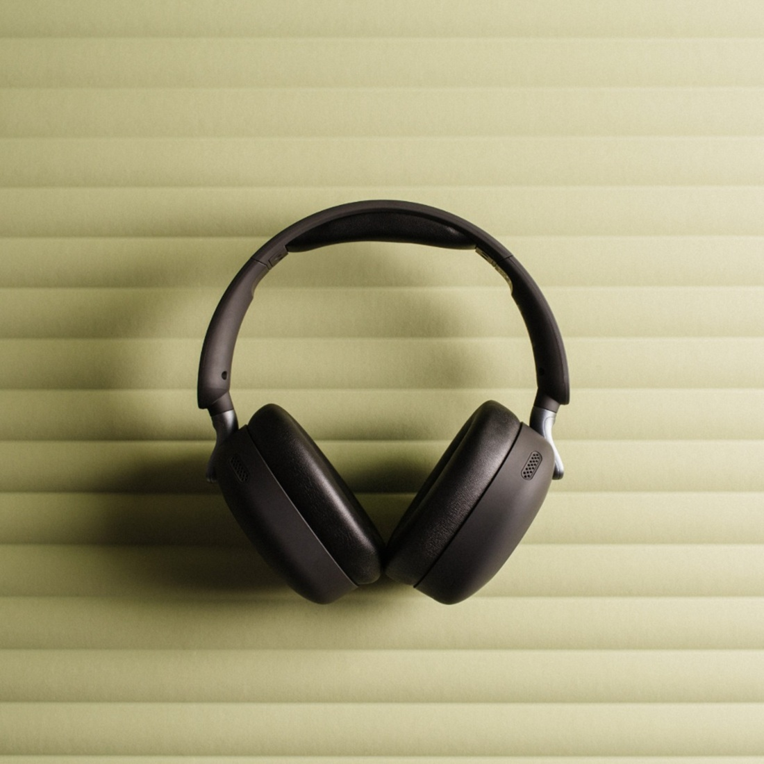 Un casque noir sur un fond vert clair texturé. Le casque est centré et légèrement incliné.