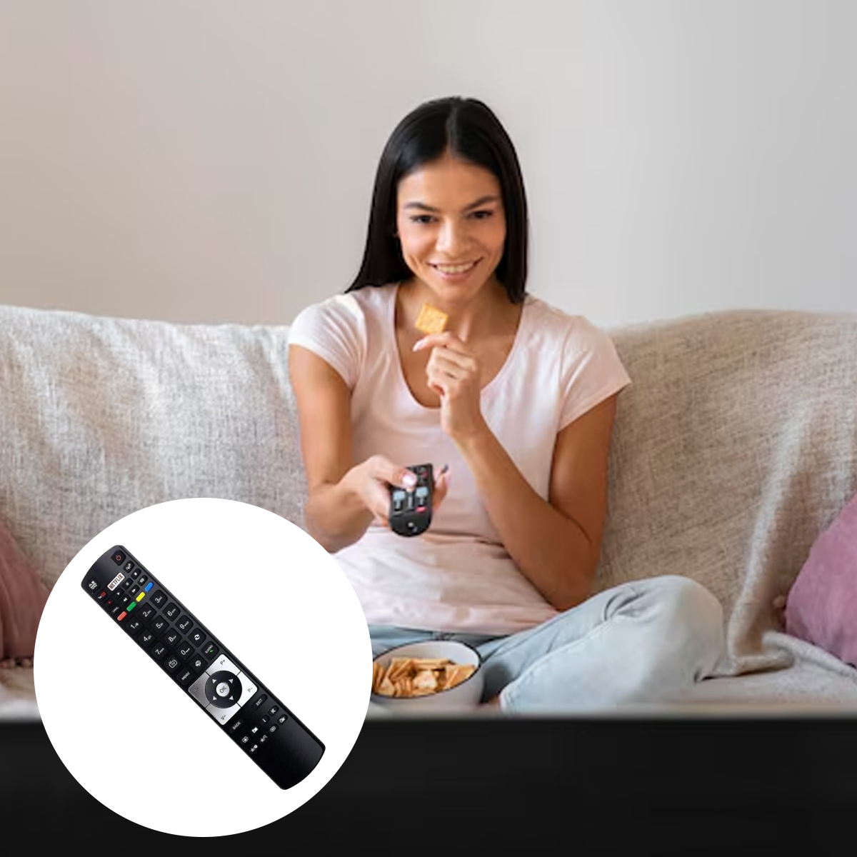 Frau auf der Couch mit Fernbedienung und Snack. Sie lächelt. Eine Schüssel Chips ist sichtbar. Eine TV-Fernbedienung ist im Vordergrund.