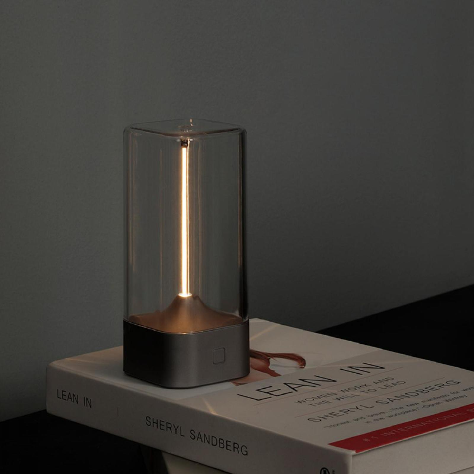Eine moderne Lampe mit vertikalem Licht steht auf einem Buch mit dem Titel 'Lean In' von Sheryl Sandberg.