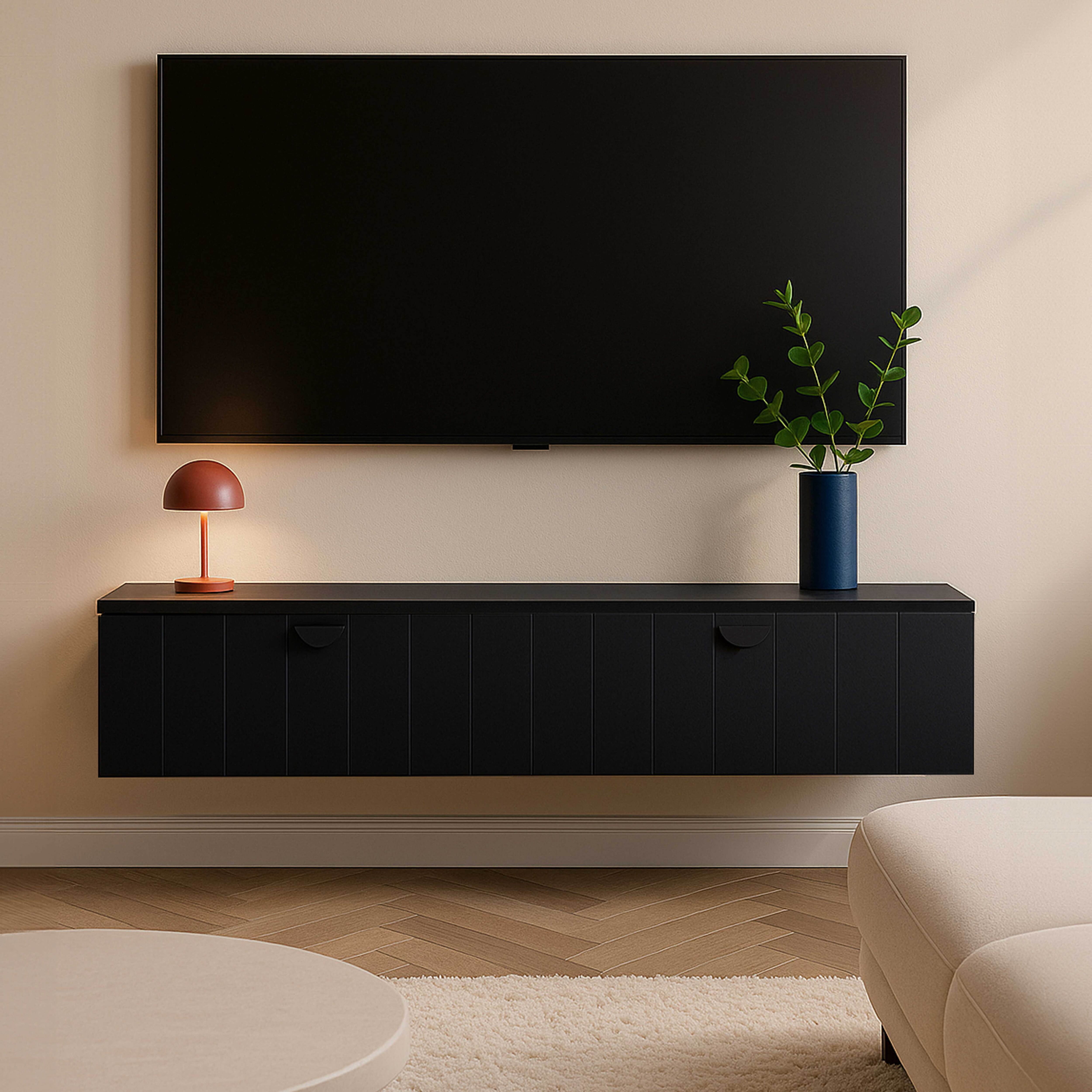 Ein schwarzer Fernseher hängt an einer beigefarbenen Wand über einem schwarzen Schrank. Eine Lampe und eine Vase stehen auf dem Schrank.