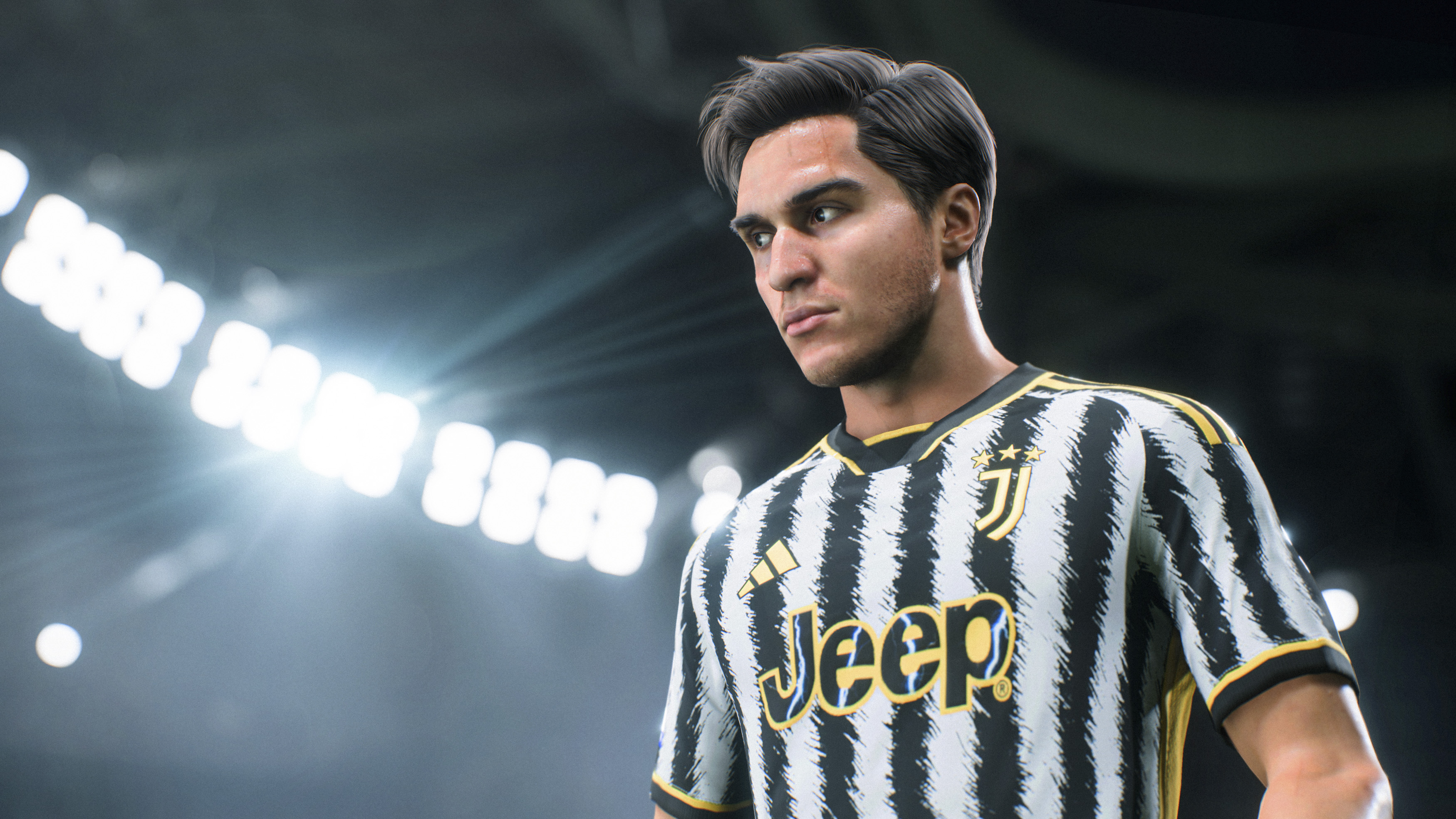 Ein Fußballspieler im Juventus-Trikot, der konzentriert wirkt. Im Hintergrund sind Stadionlichter und dunkler Himmel zu sehen.