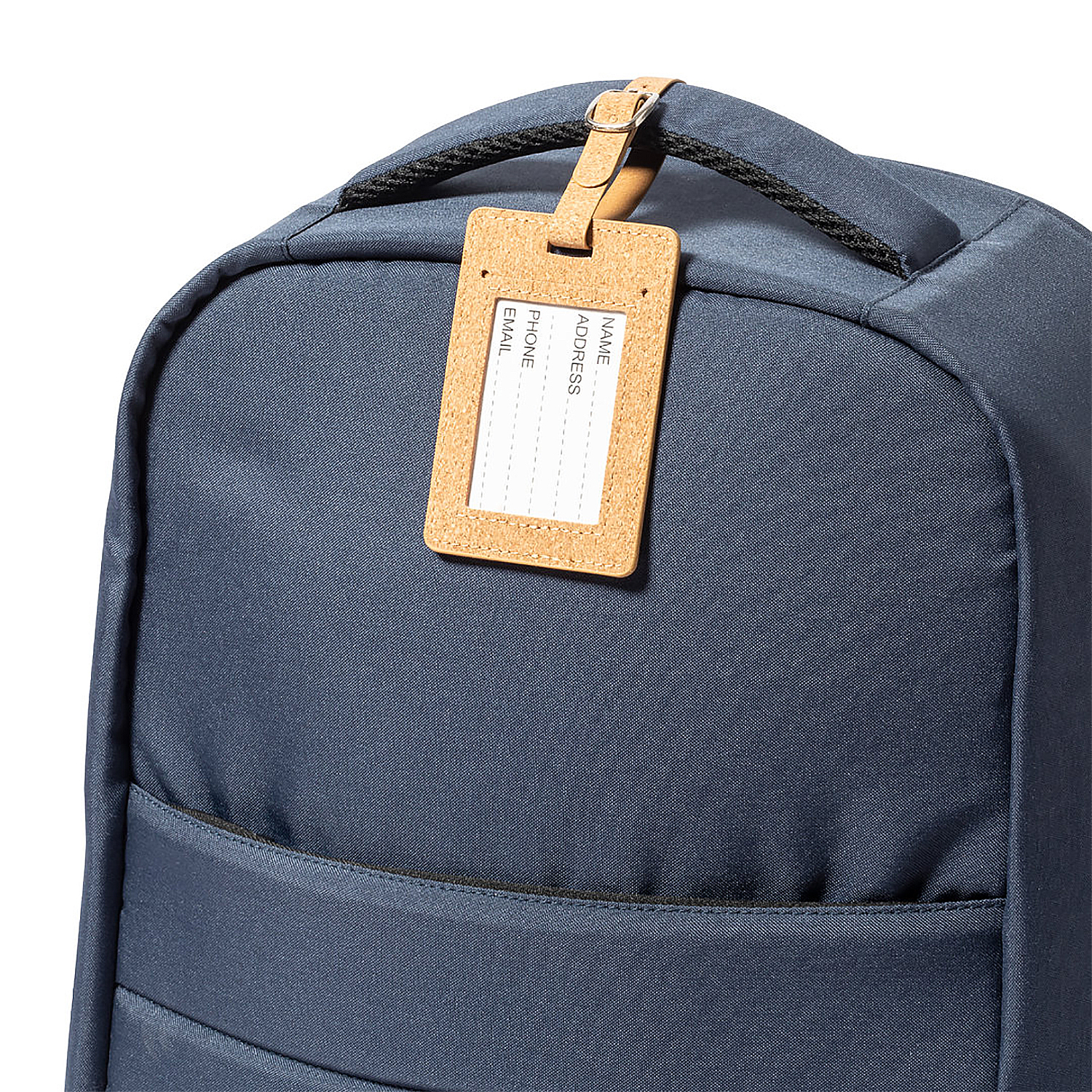 Una mochila azul marino con una etiqueta de equipaje de corcho adjunta a su asa. La etiqueta tiene líneas para nombre, dirección, teléfono y correo electrónico.