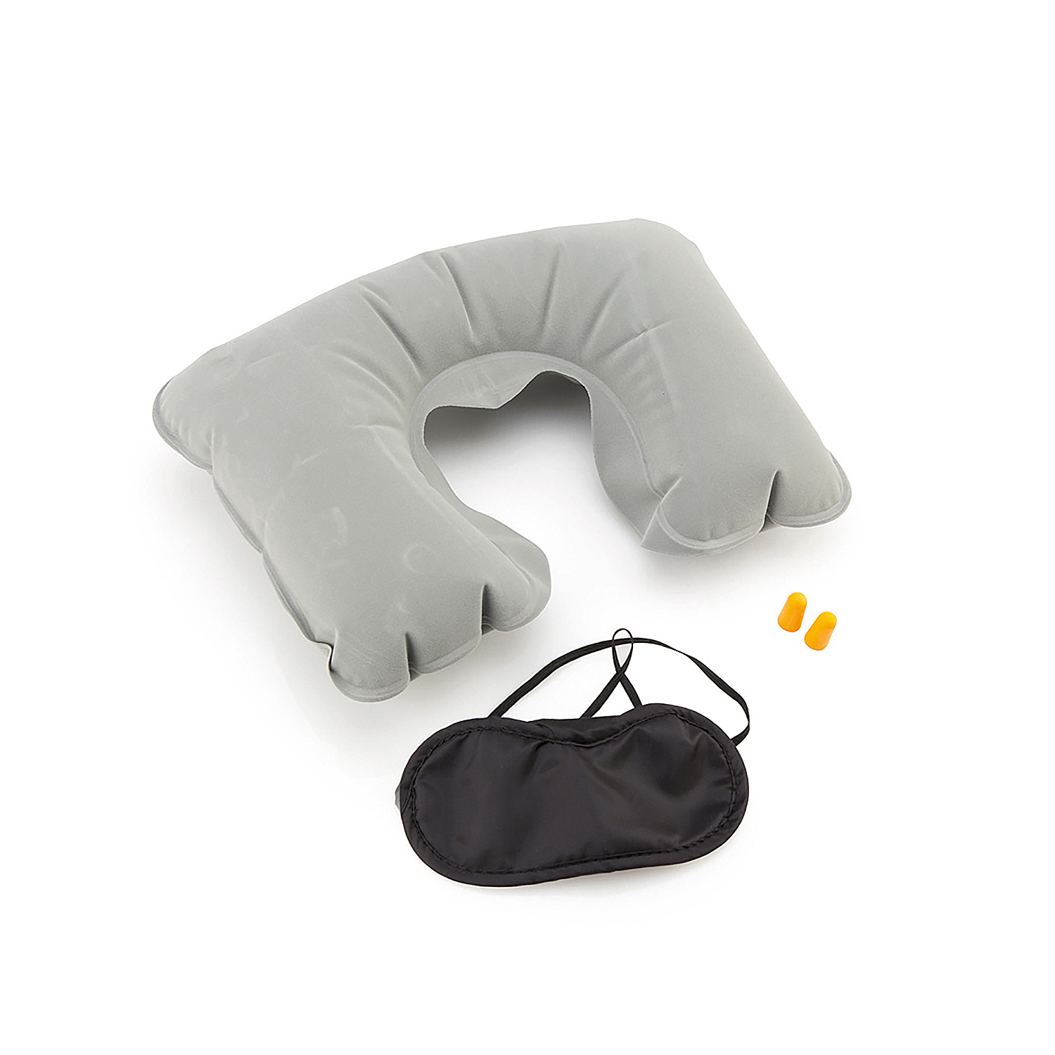 Una almohada de viaje gris, una máscara para los ojos negra y dos tapones para los oídos naranjas sobre una superficie blanca.