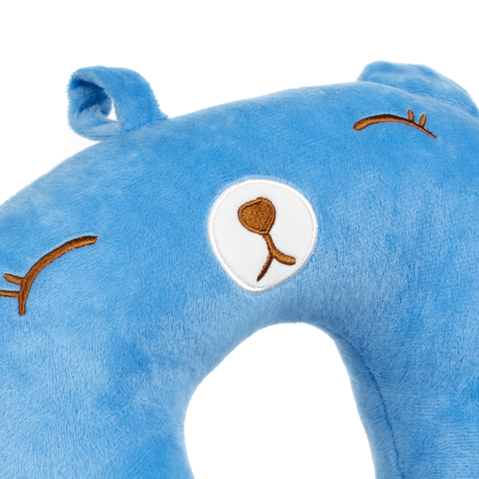 Una almohada de viaje azul y afelpada con forma de cabeza de oso. Tiene rasgos bordados marrones sobre un fondo blanco.