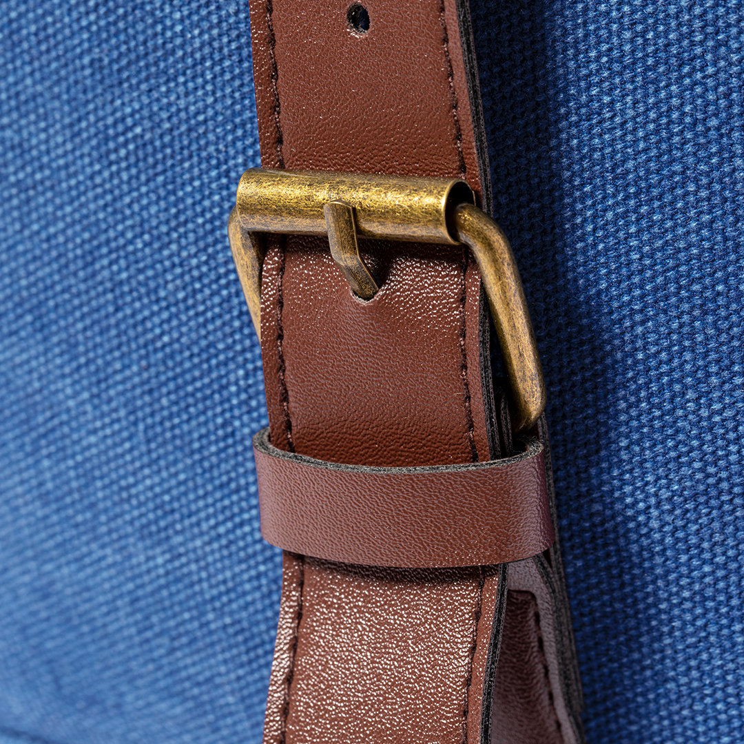 Primo piano di un cinturino in pelle marrone con fibbia color oro su sfondo blu in tela.