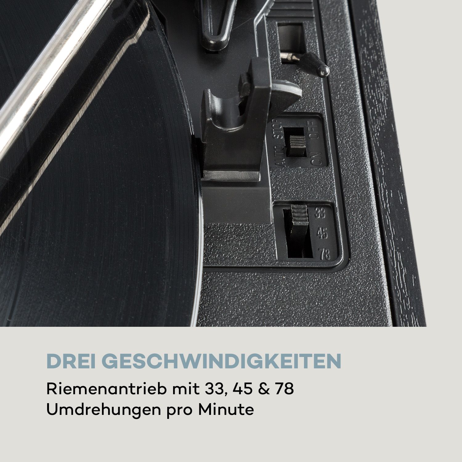 Nahaufnahme eines Plattenspielers. Schwarze Schallplatte, silberner Arm und Bedienfeld mit Geschwindigkeitsoptionen. Text: Drei Geschwindigkeiten.